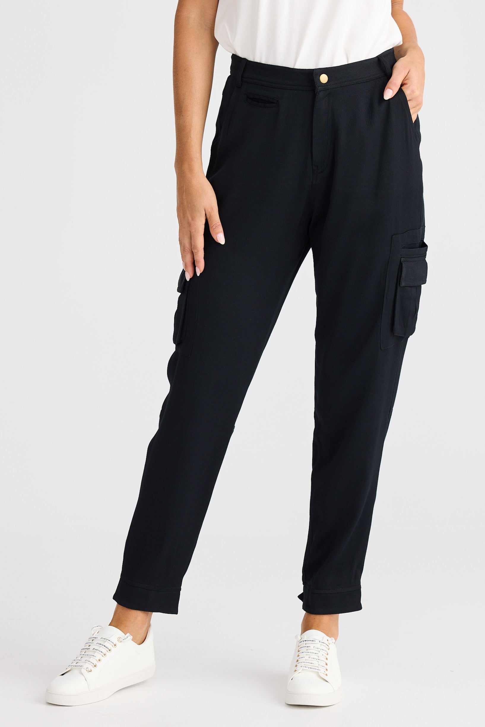 Person wearing black cargo pants and white sneakers on a white background