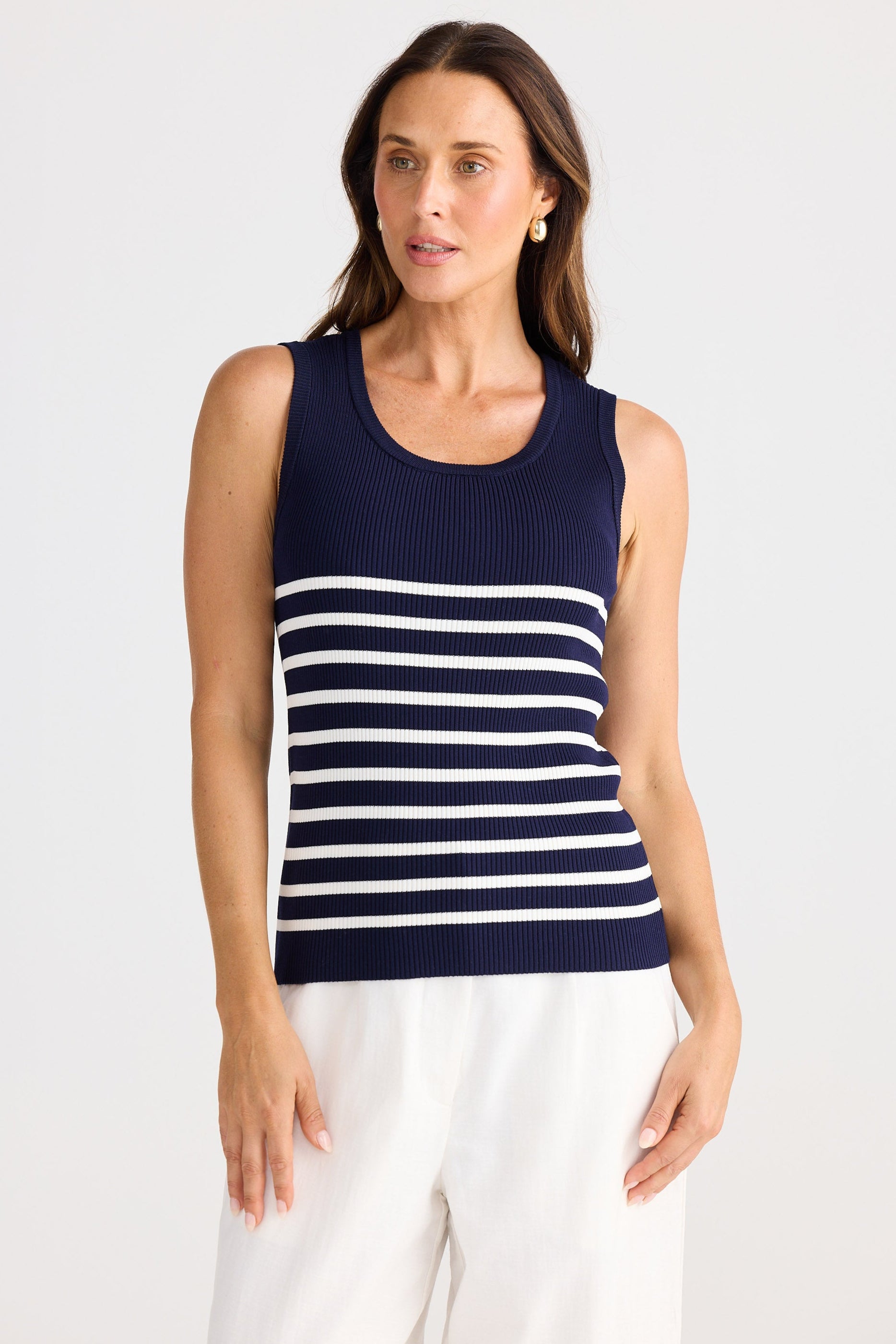 Woman wearing a navy and white striped sleeveless top against a white background