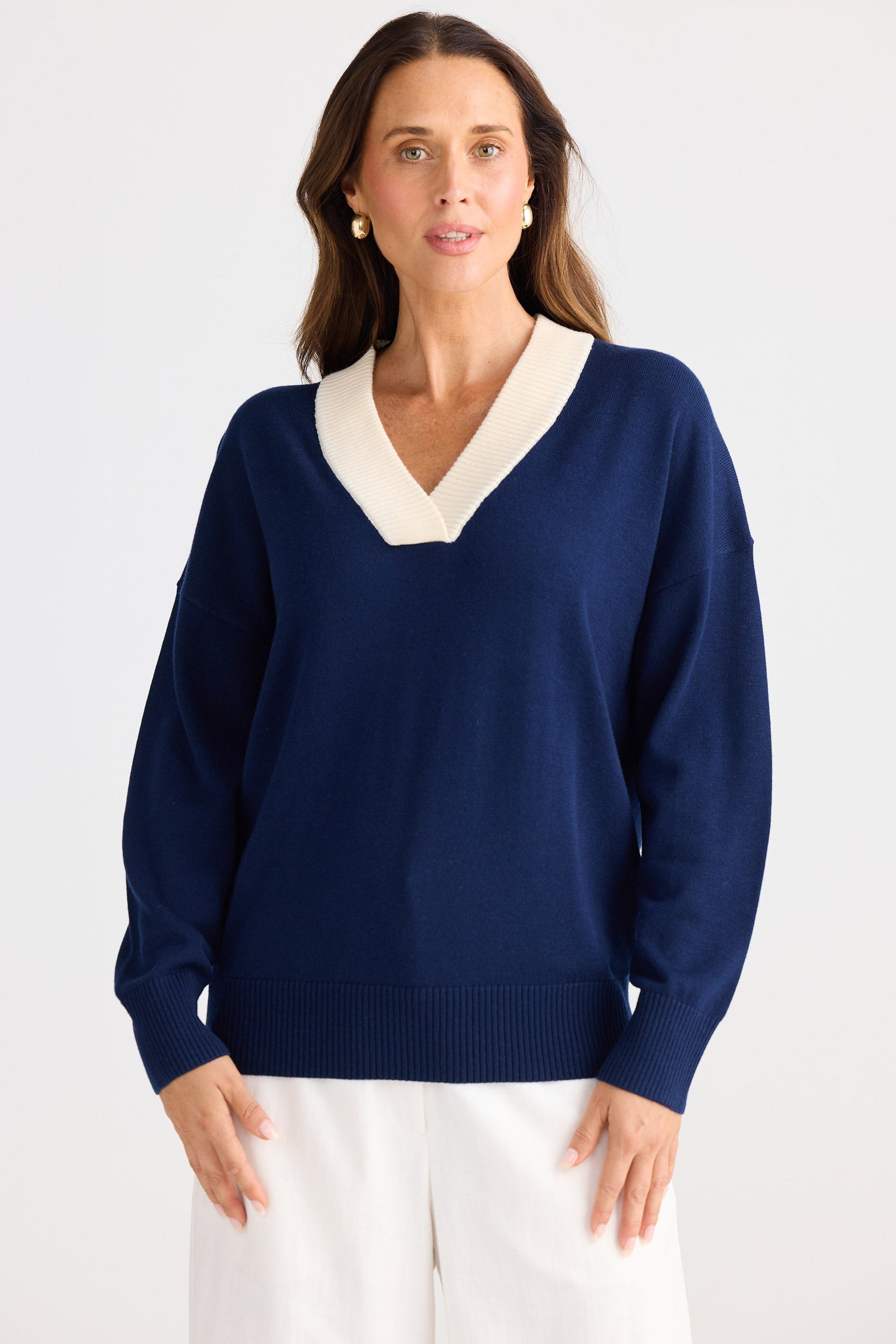 Woman wearing a navy sweater with a white collar against a light background