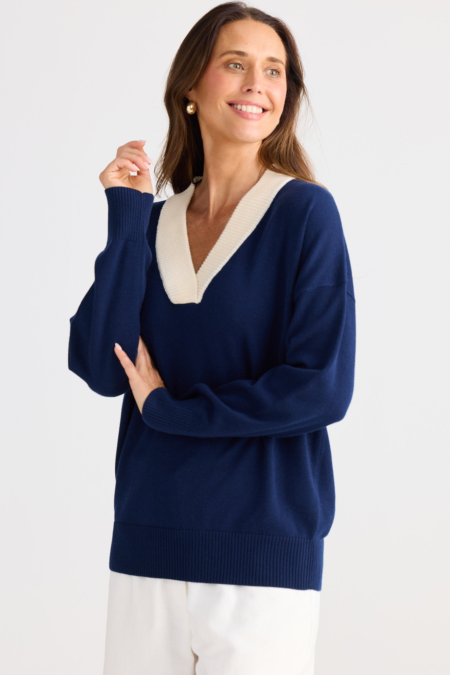 Woman wearing a navy sweater with a white collar against a white background