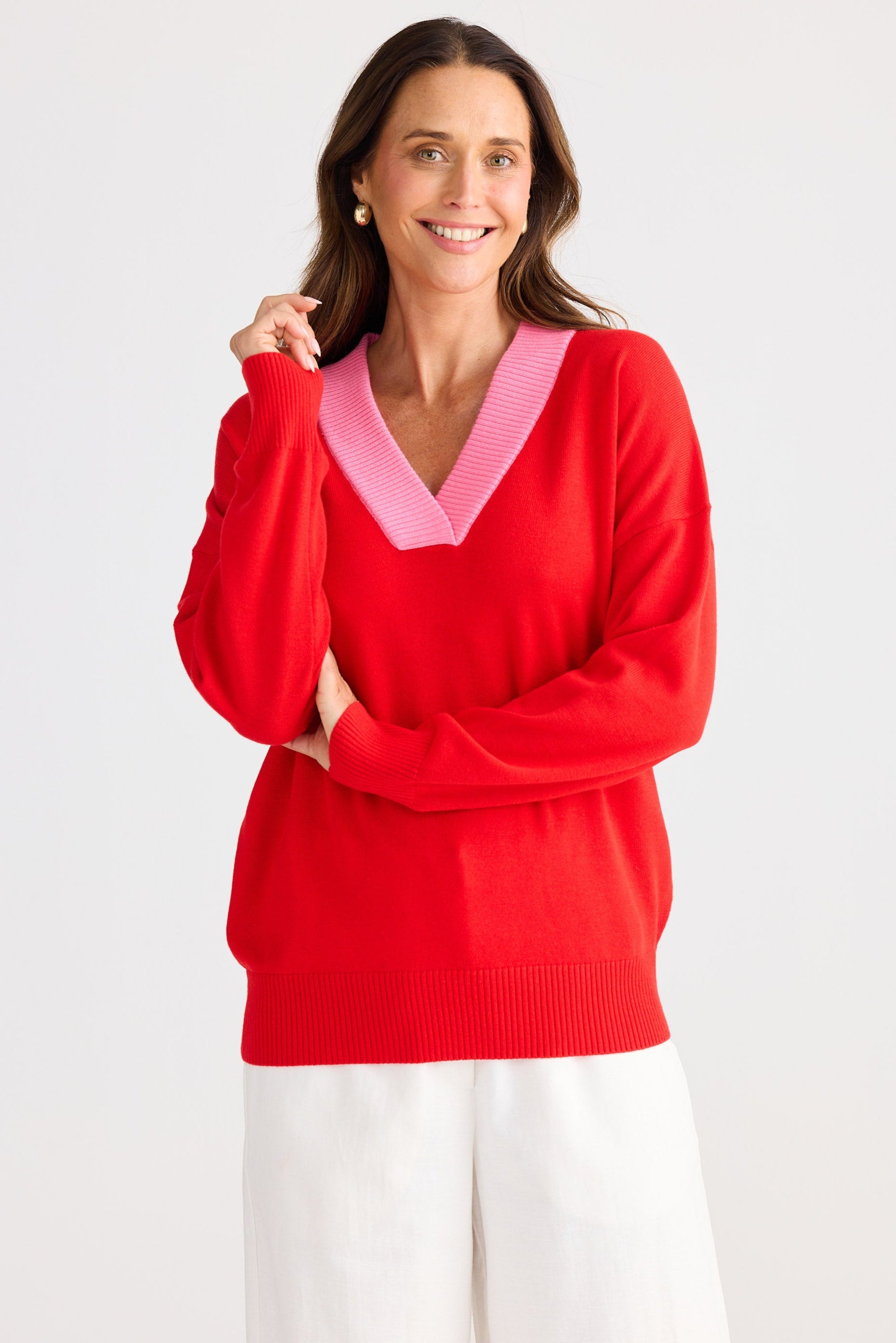 Woman wearing a red sweater with a pink collar on a white background