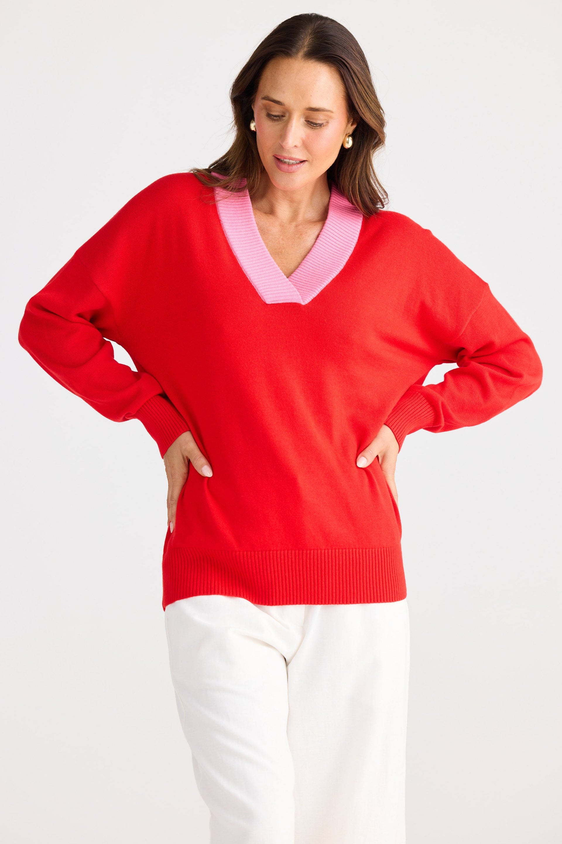 Woman wearing a red sweater with a pink collar on a white background