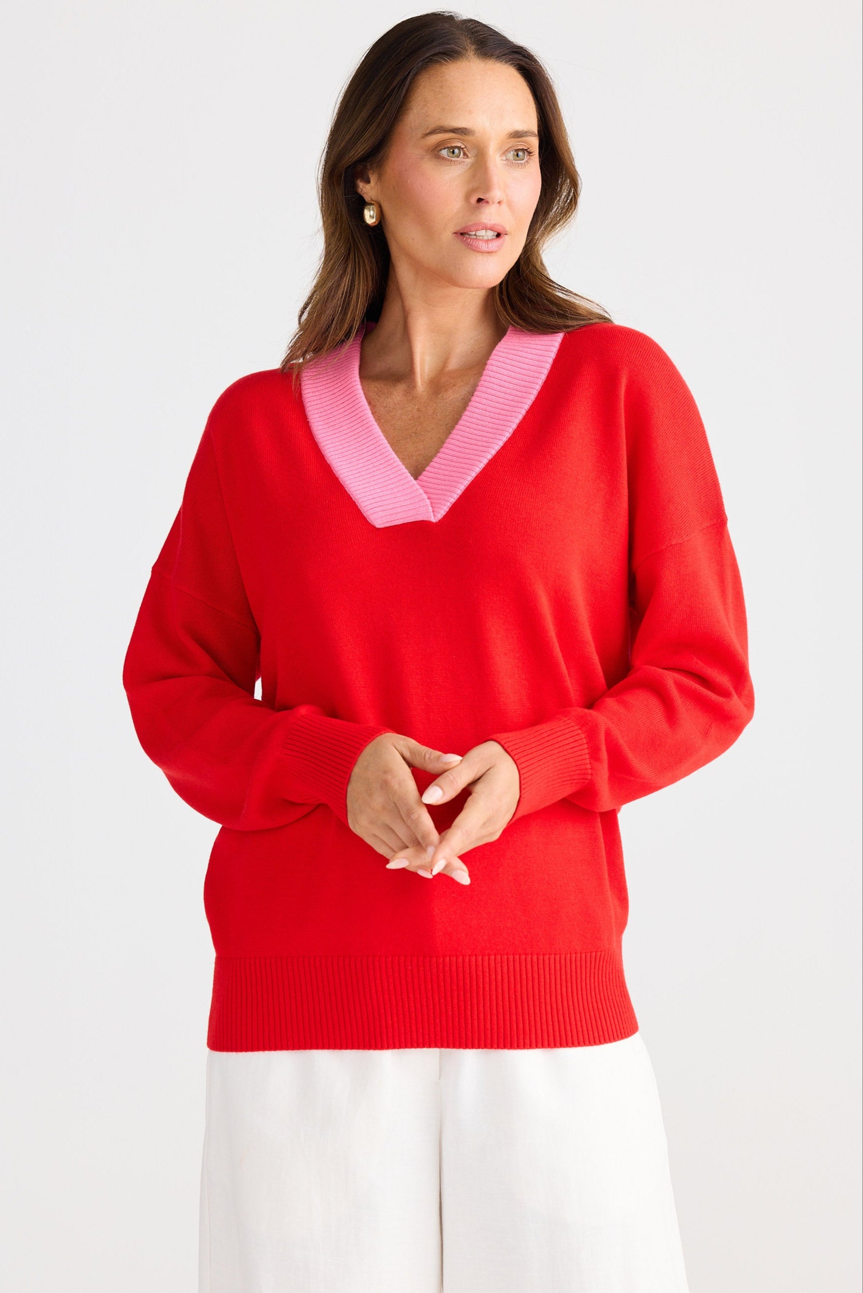Woman wearing a red sweater with pink collar against a white background