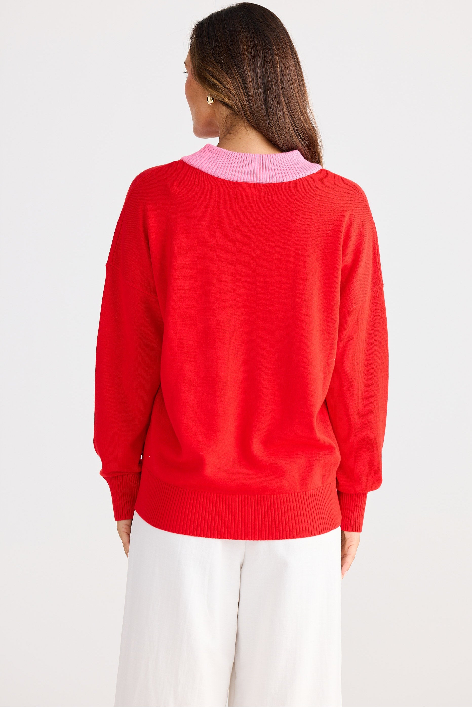 Person wearing a red sweater with a pink collar on a white background