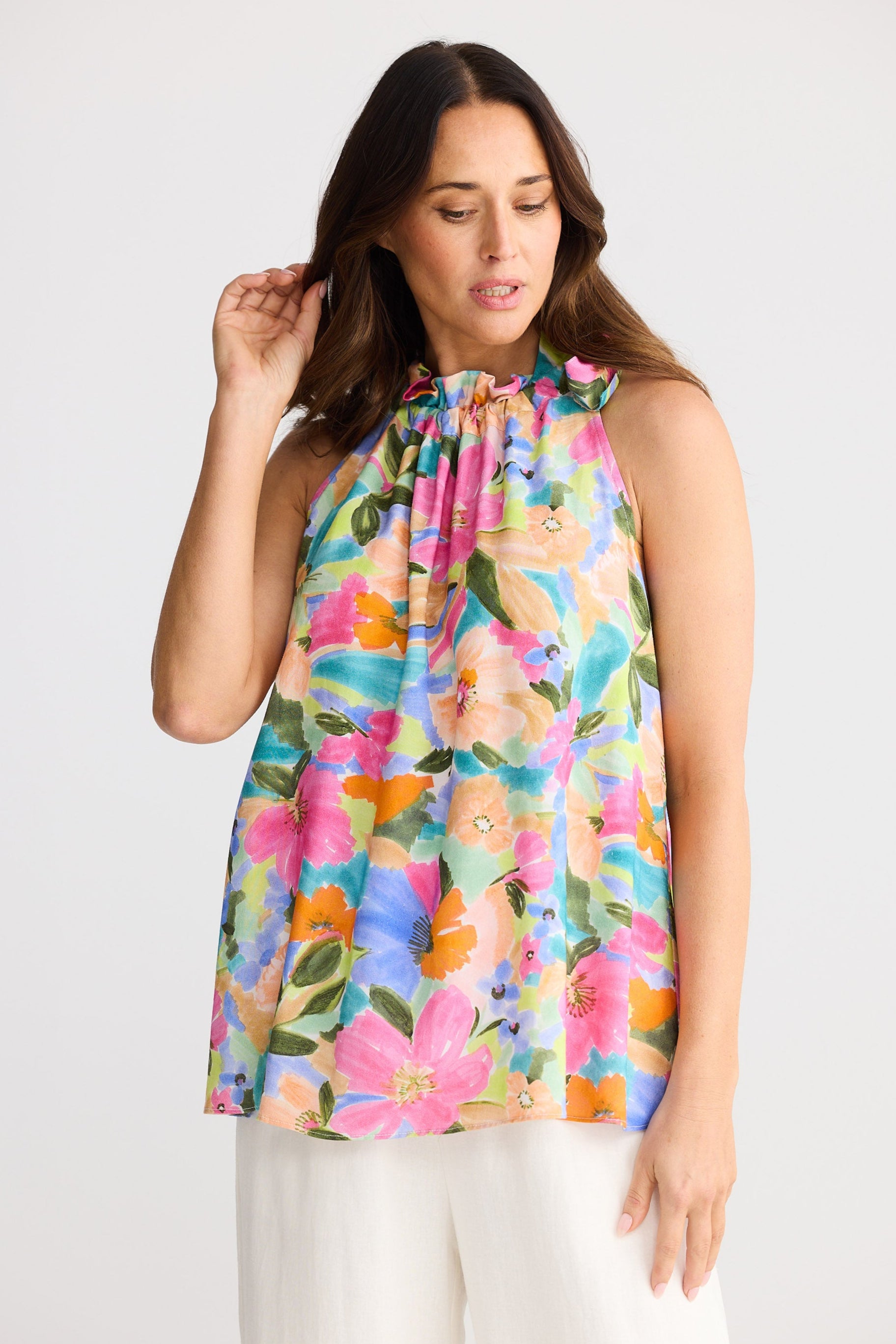 Woman wearing a colorful floral sleeveless top against a white background