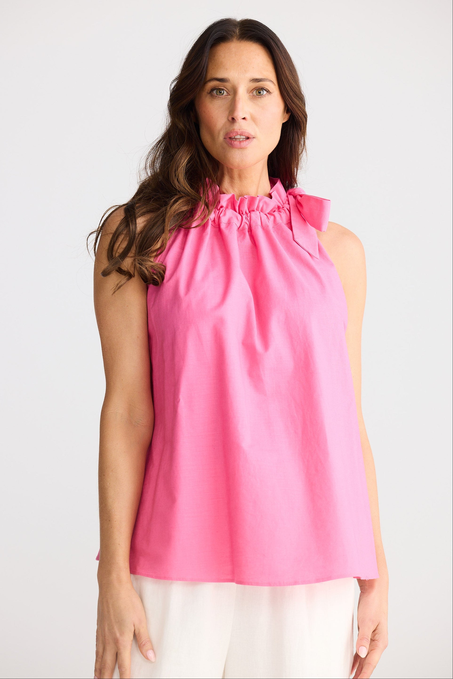 Woman wearing a pink sleeveless top against a white background