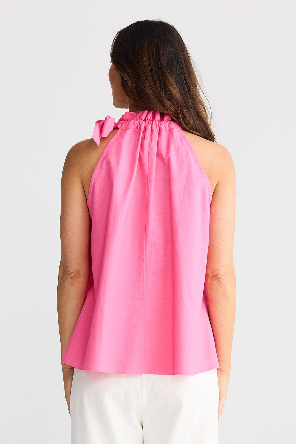 Woman wearing a pink top with a bow detail on a white background