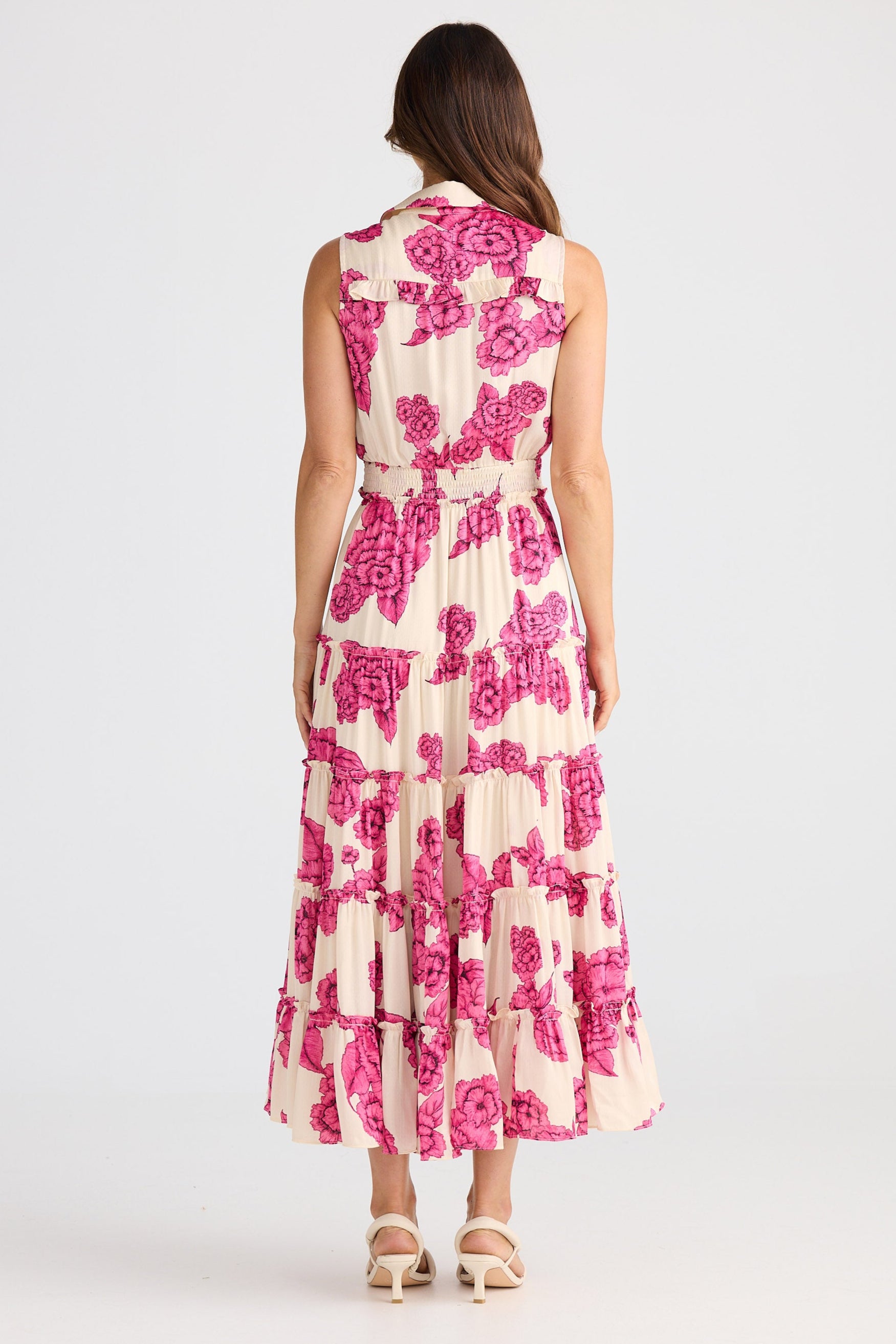 Woman wearing a sleeveless floral dress with pink flowers on a white background