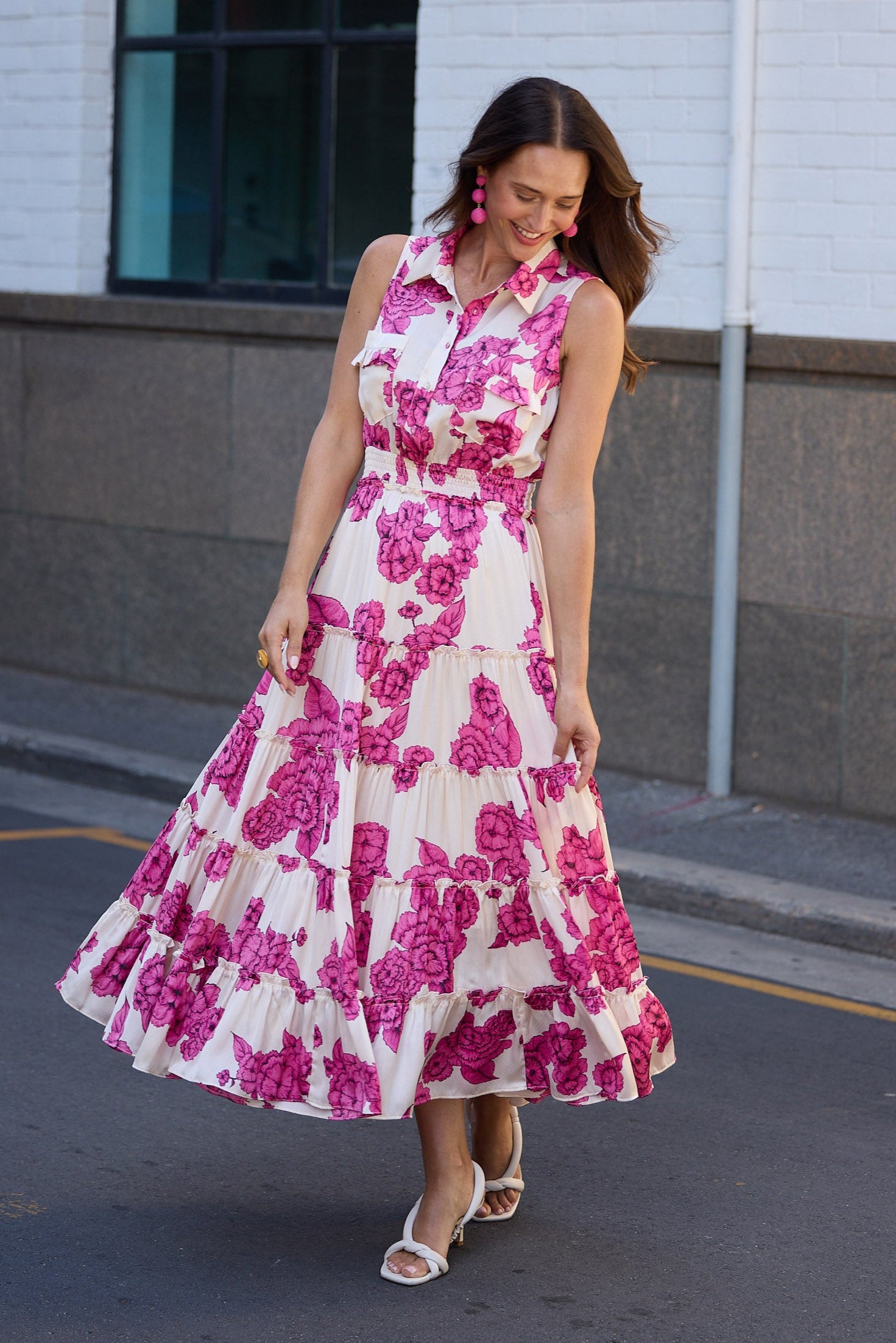 Woman in a pink floral dress standing on a street.