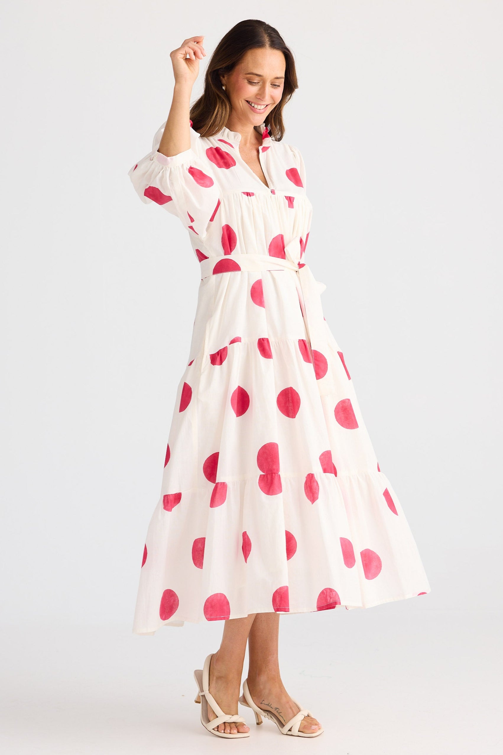 Woman wearing a white dress with pink polka dots on a white background