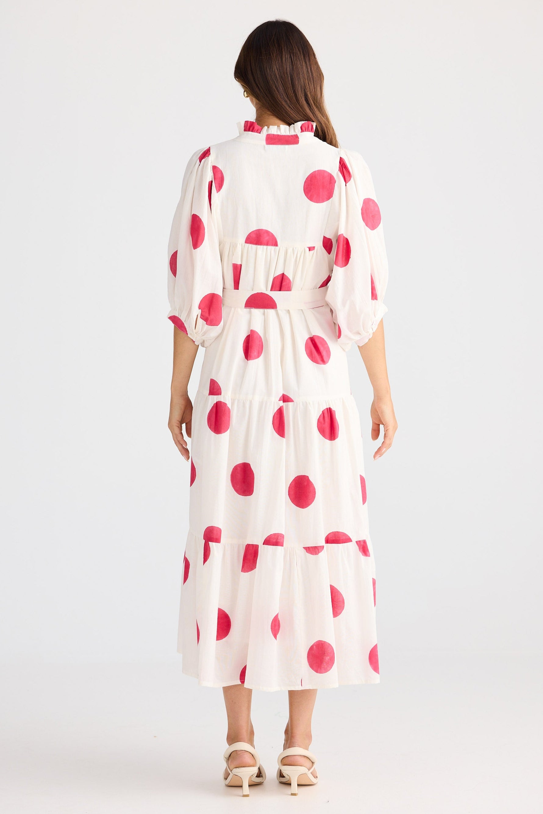 Woman wearing a white dress with pink polka dots on a white background