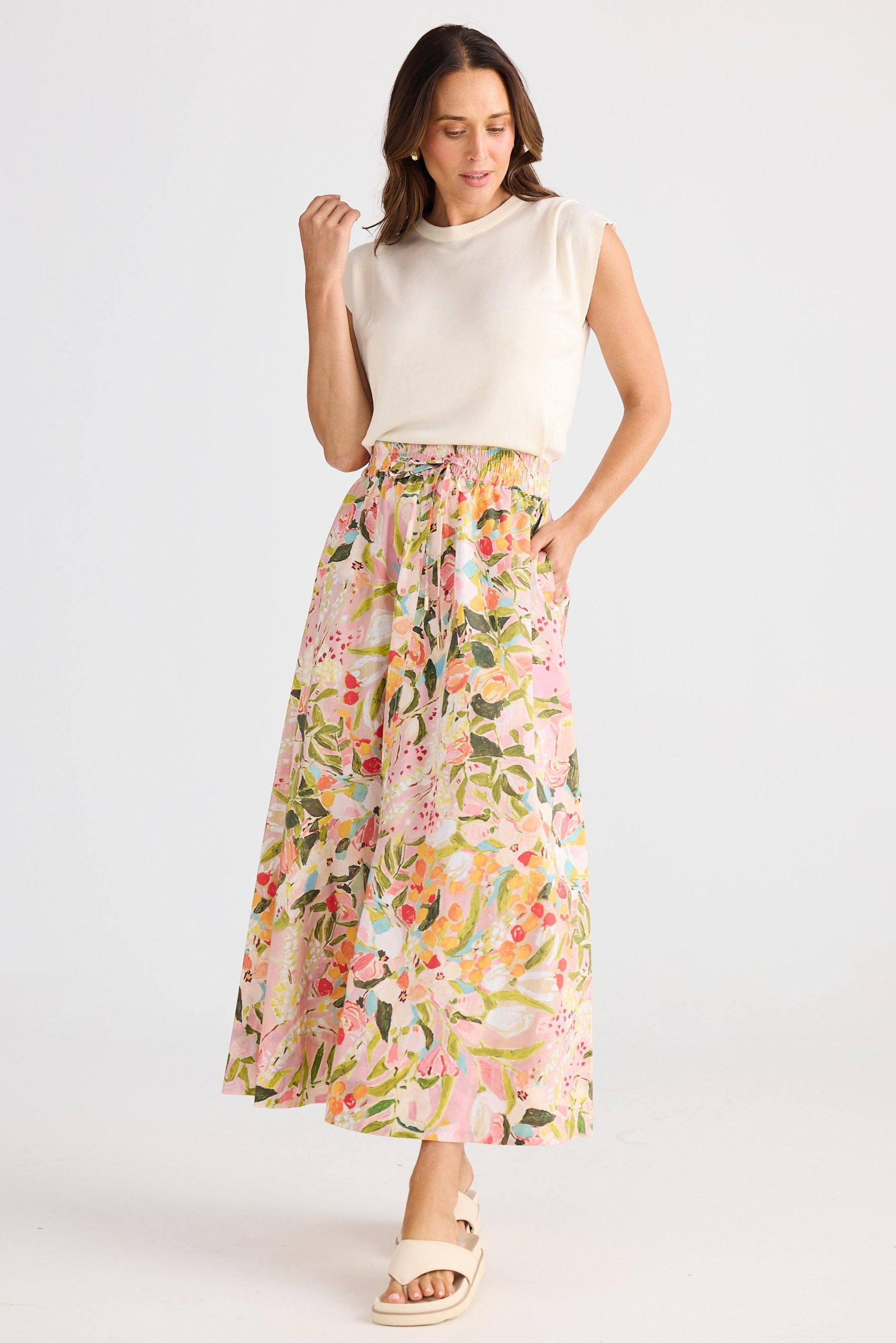 Woman wearing a floral skirt and white top on a white background
