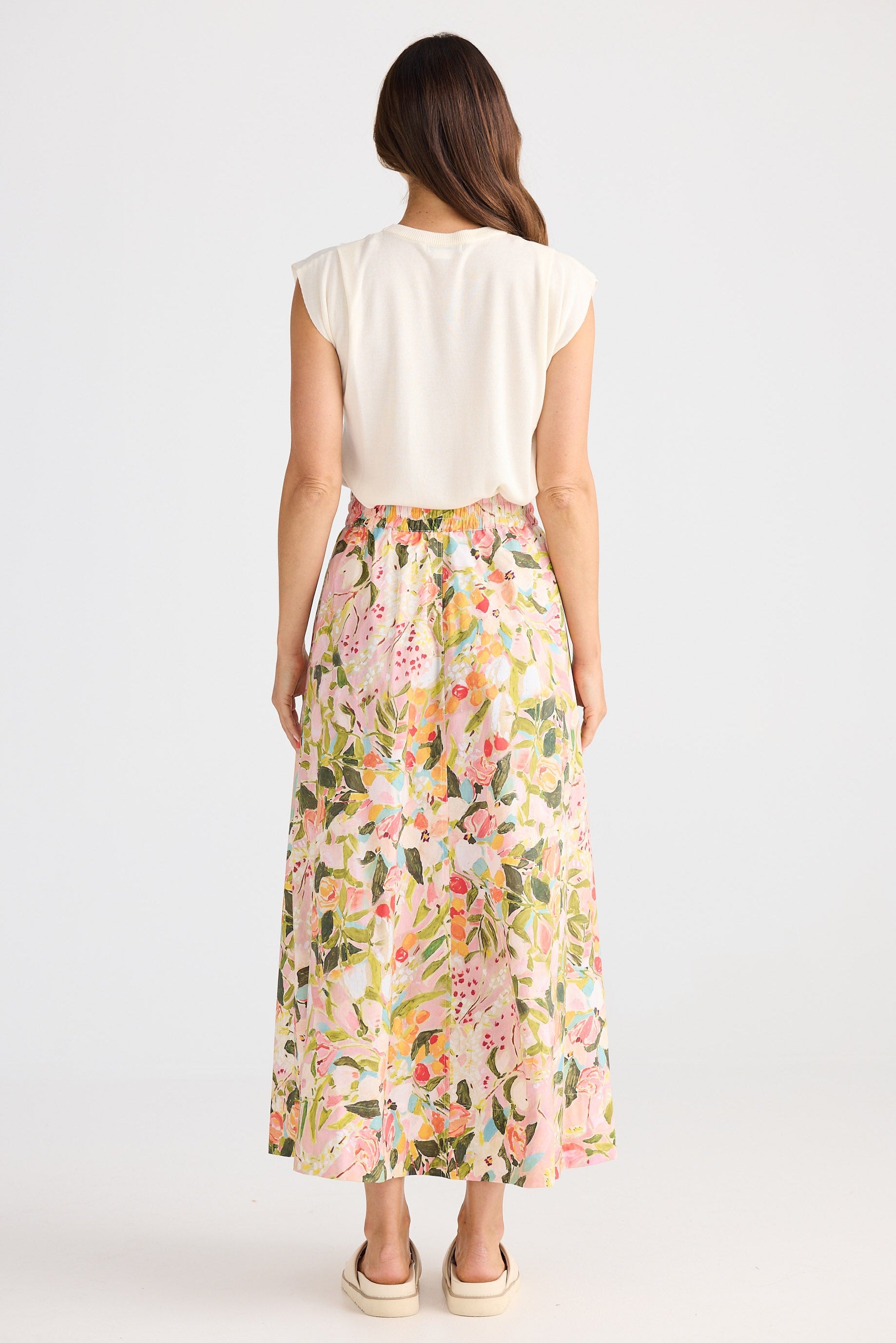 Woman wearing a white top and floral skirt on a white background