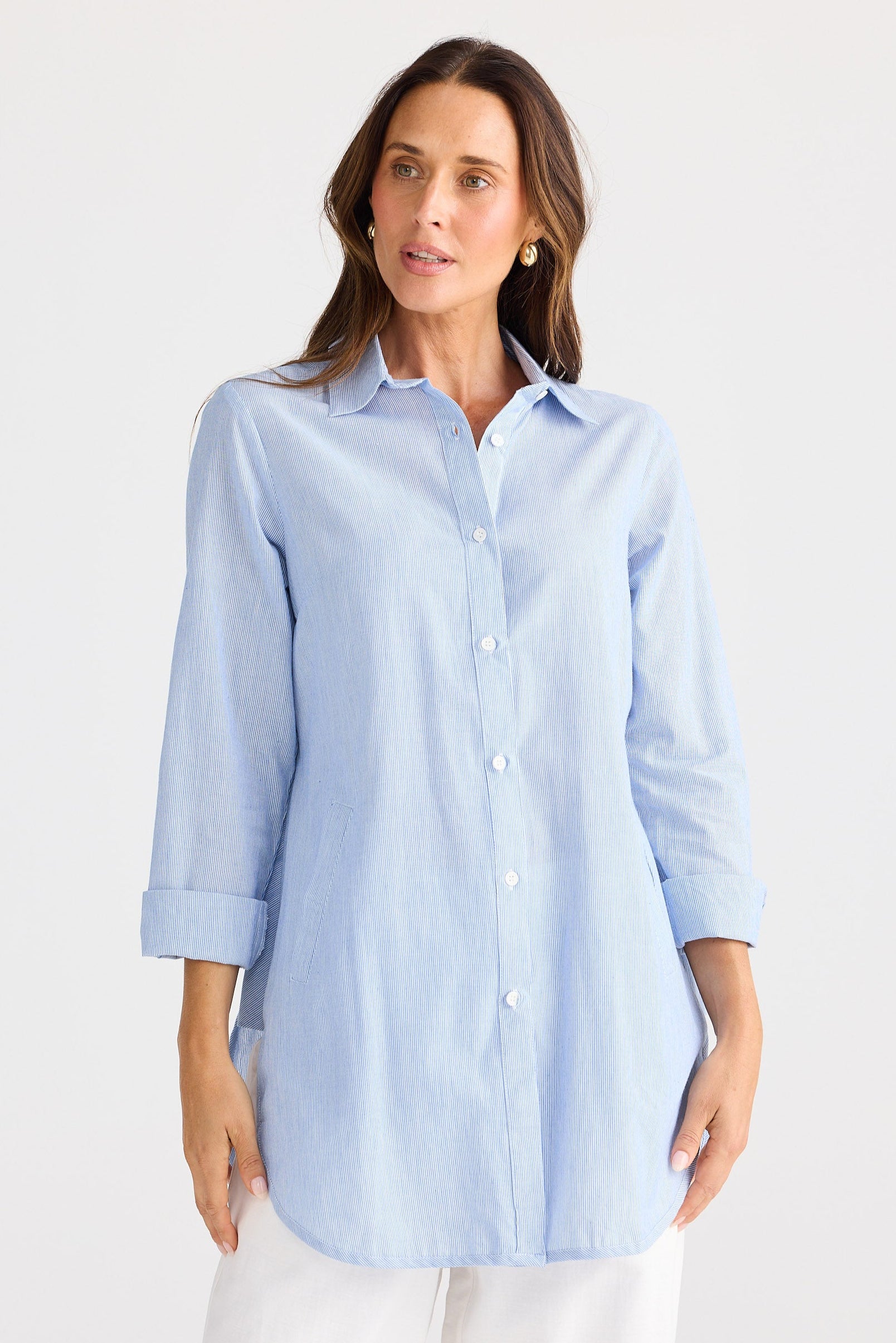 Woman wearing a light blue button-up shirt on a white background