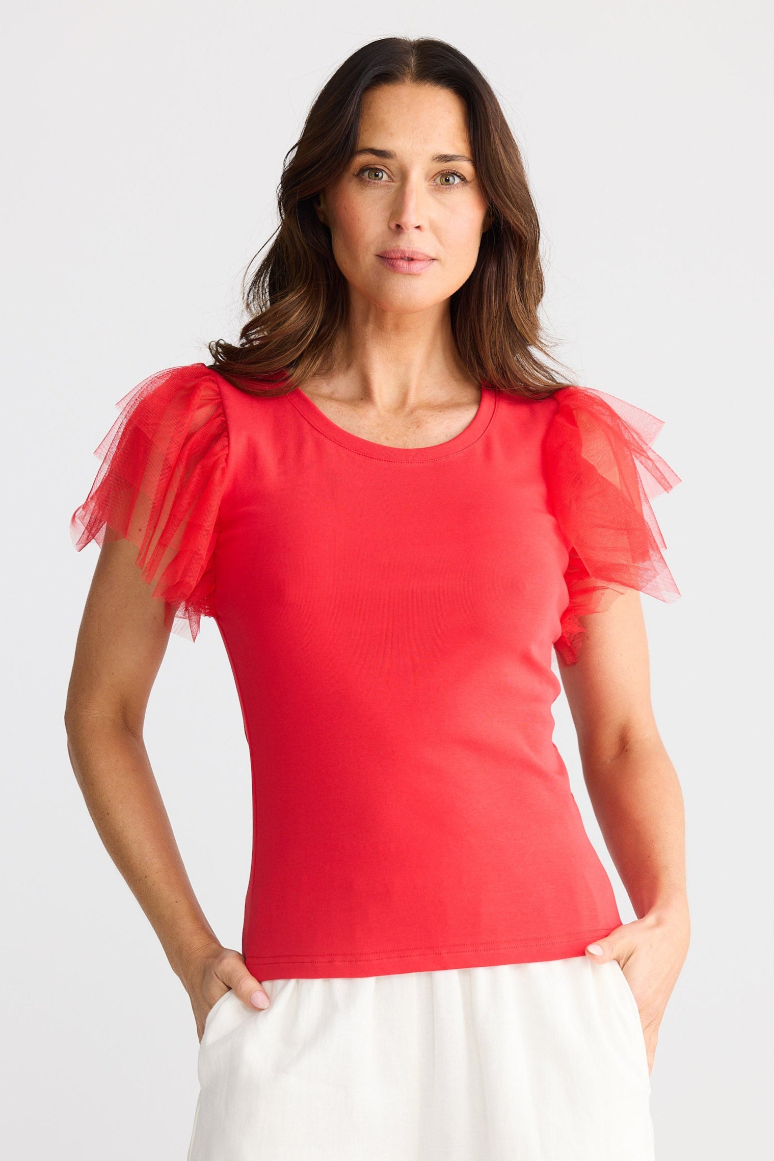 Woman wearing a red top with tulle sleeves on a white background