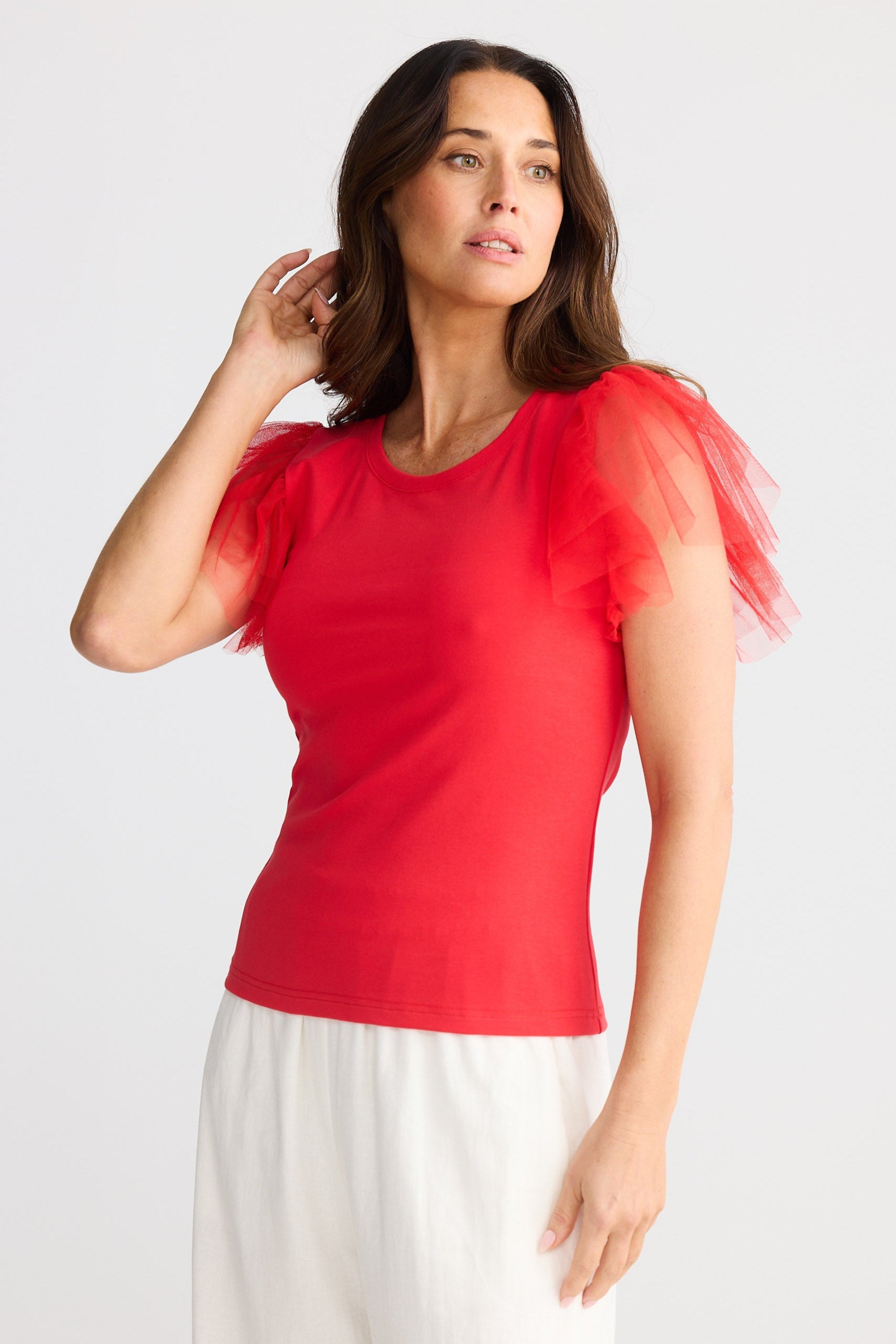 Woman wearing a red top with sheer sleeves on a white background