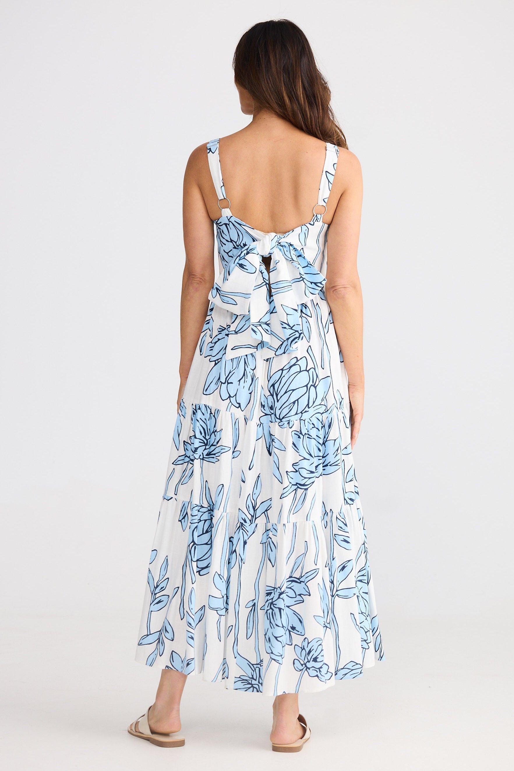 Woman wearing a floral dress with blue and white flowers on a plain background