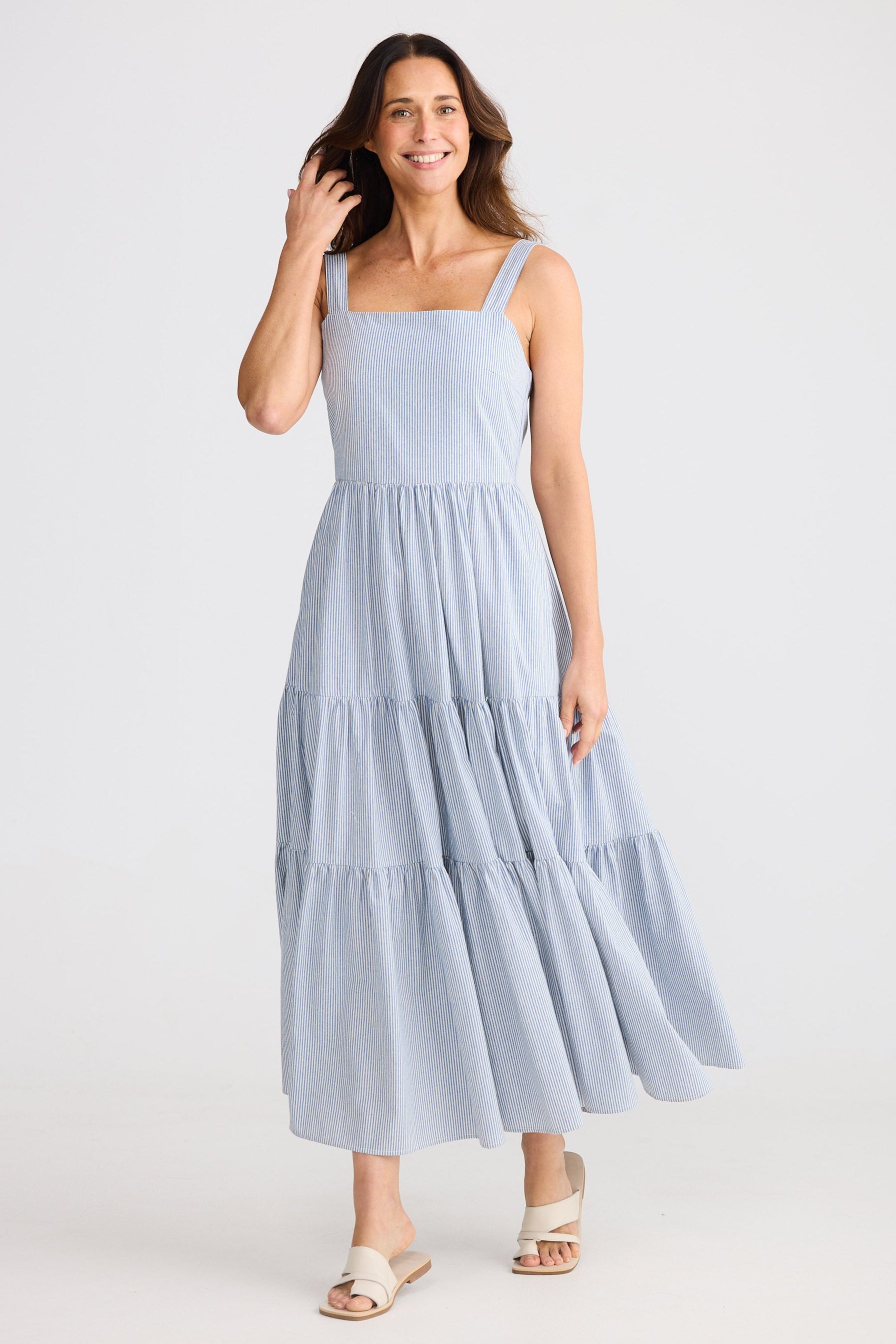 Woman wearing a light blue tiered dress on a white background