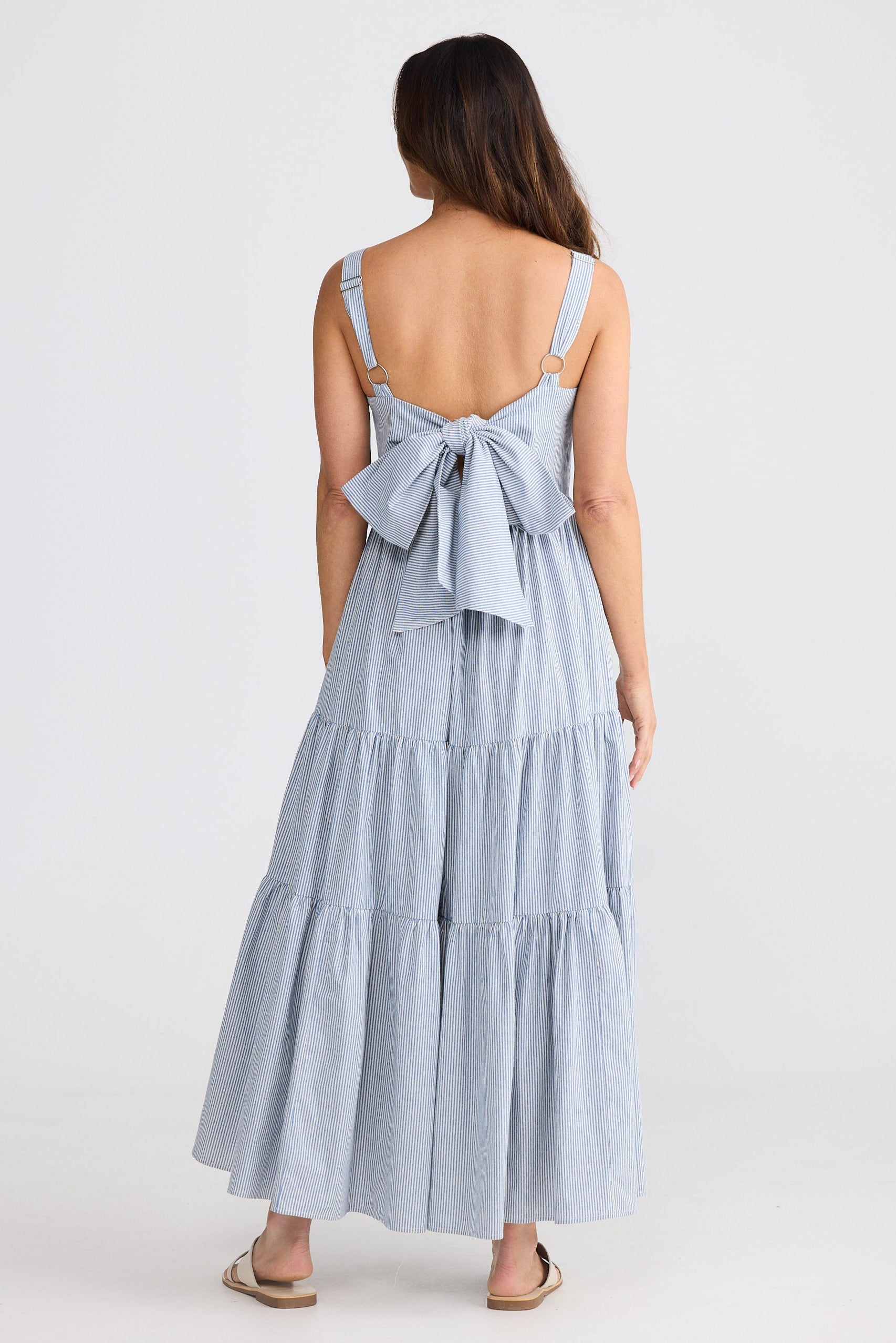 Woman wearing a light blue dress with a bow detail on a white background