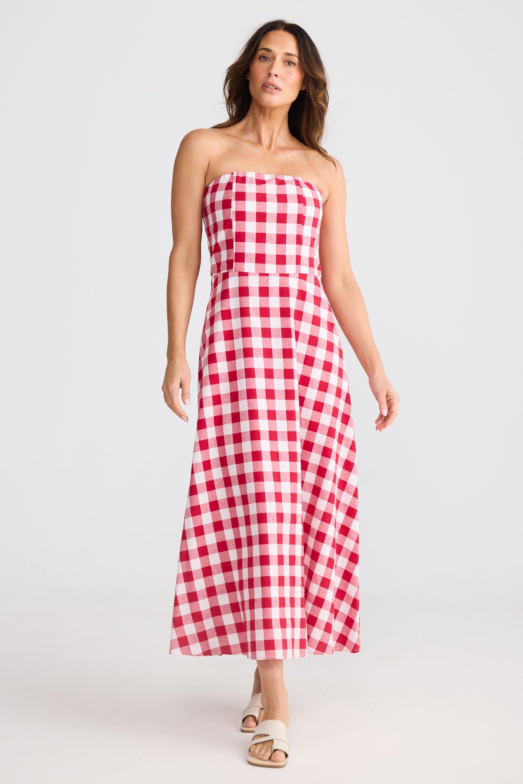 Woman wearing a red and white checkered strapless dress on a white background