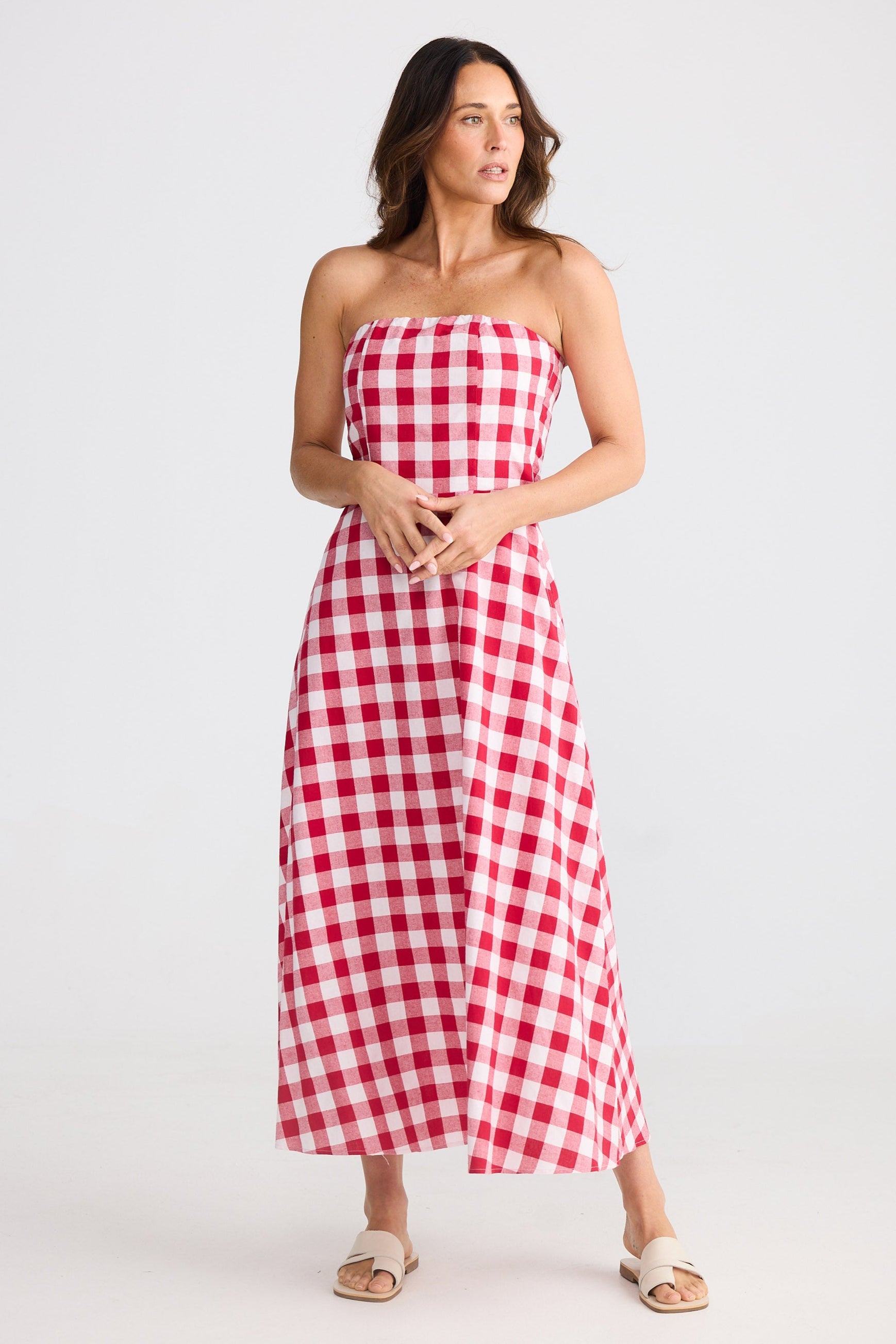 Woman wearing a red and white checkered strapless dress on a white background