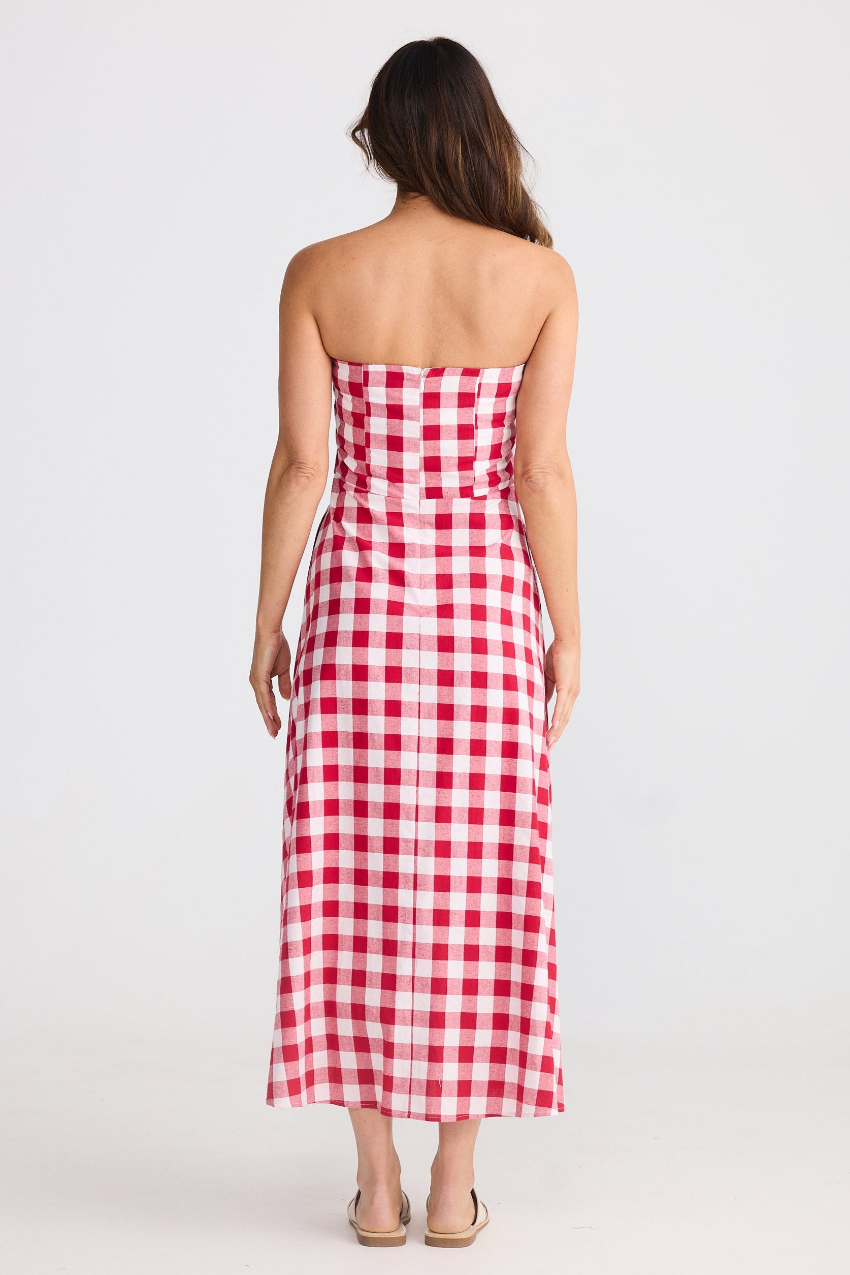 Woman wearing a red and white checkered strapless dress on a white background