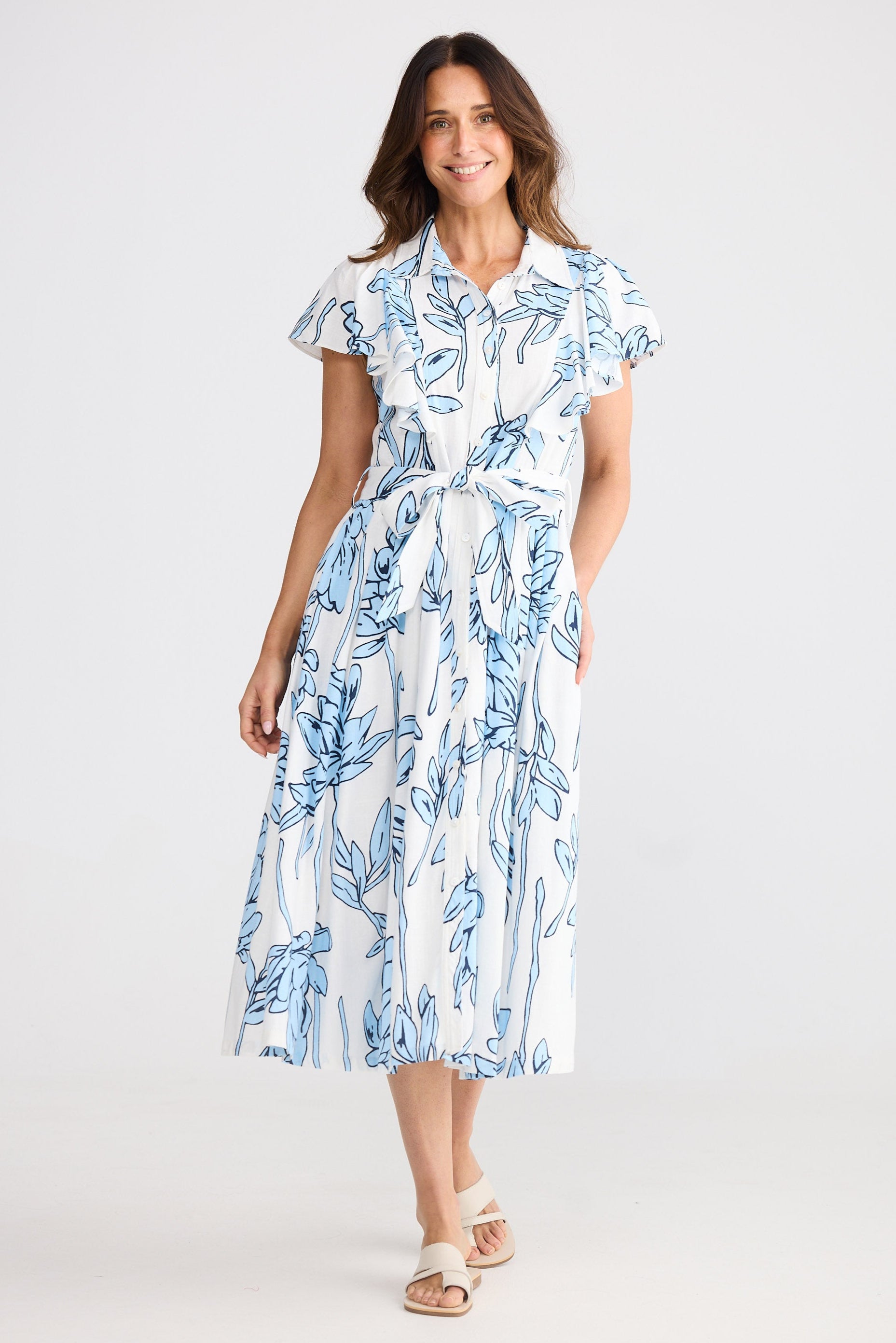 Woman wearing a blue and white floral dress on a plain background