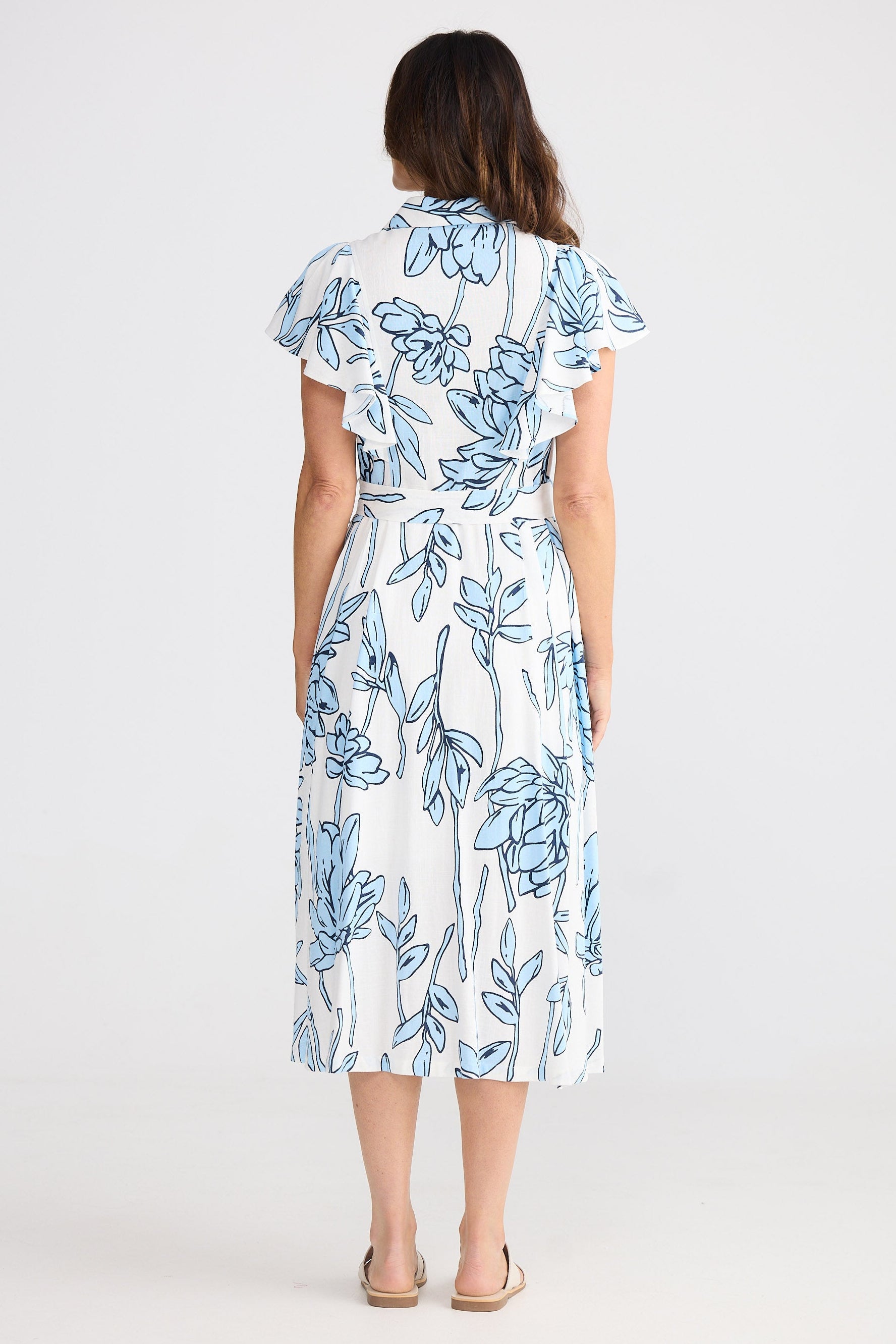 Woman wearing a white dress with blue floral pattern on a white background