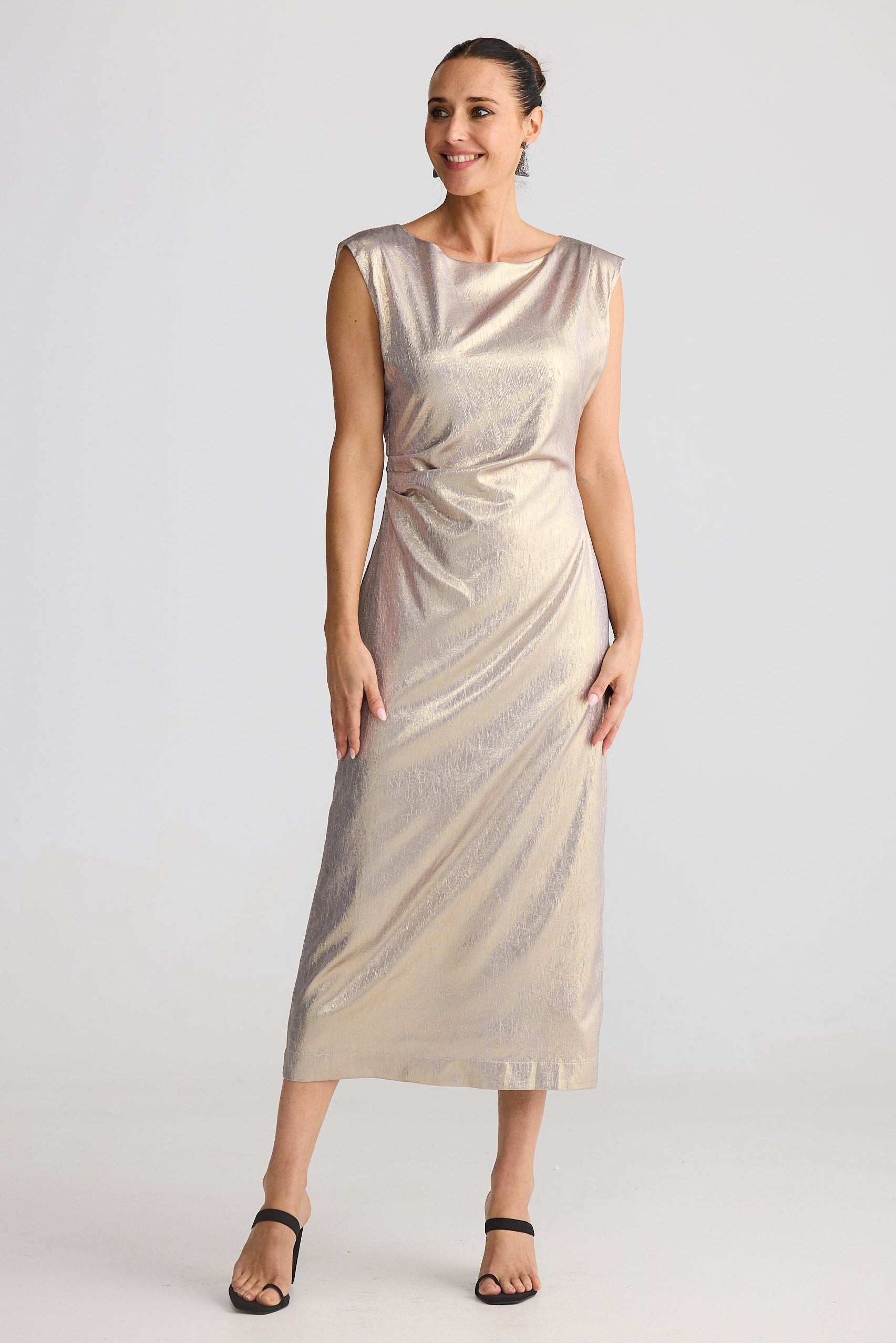 Woman wearing a gold metallic dress on a light gray background