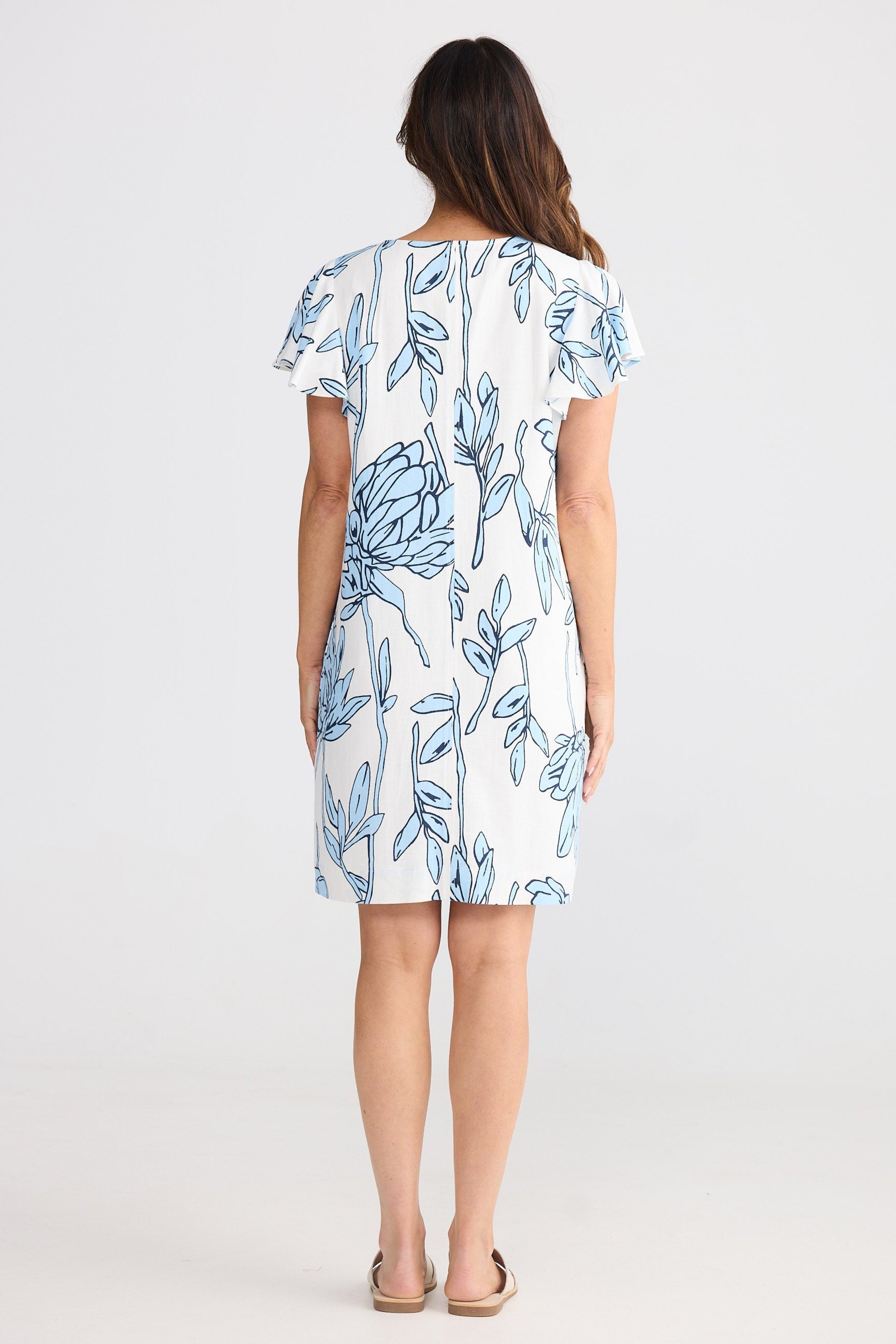 Woman wearing a white dress with blue floral patterns on a white background