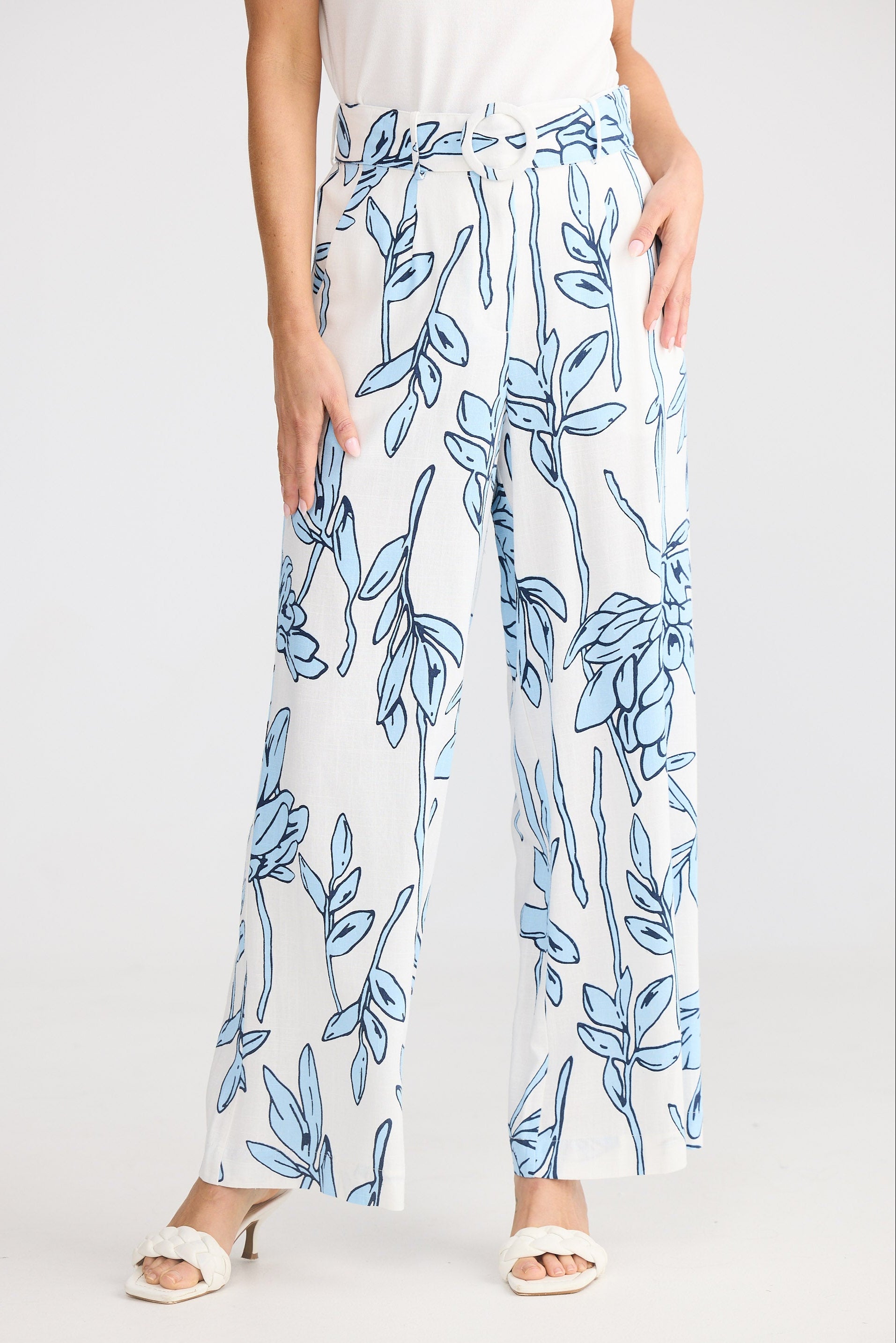 White pants with blue leaf pattern worn by a person on a white background