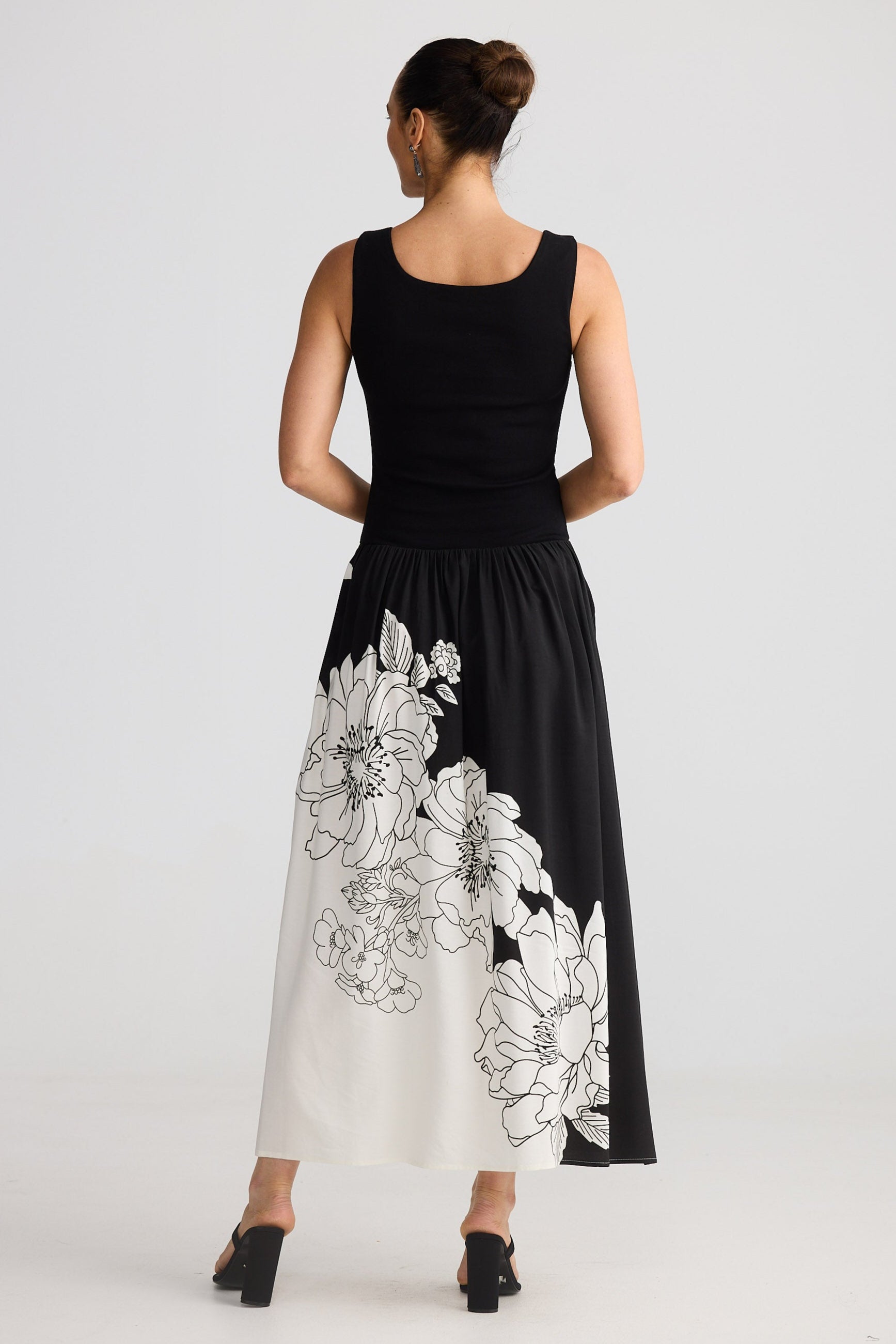 Woman wearing a black dress with white floral patterns on a plain background