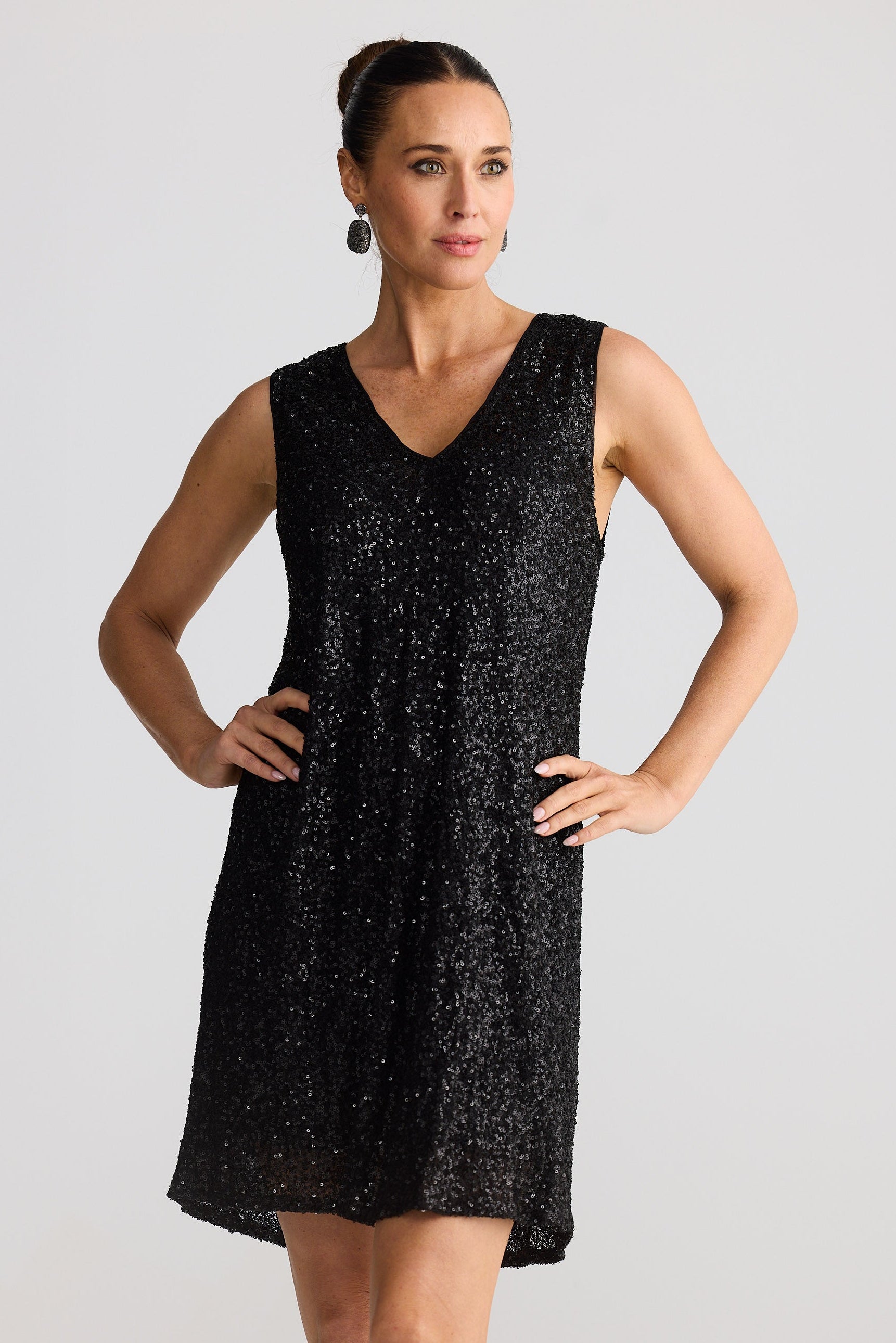 Woman wearing a black sequin dress against a plain background