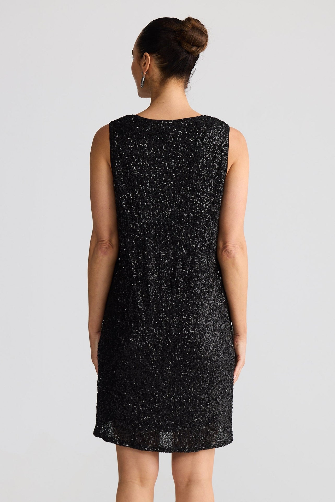 Woman wearing a black sleeveless dress with a subtle pattern on a white background