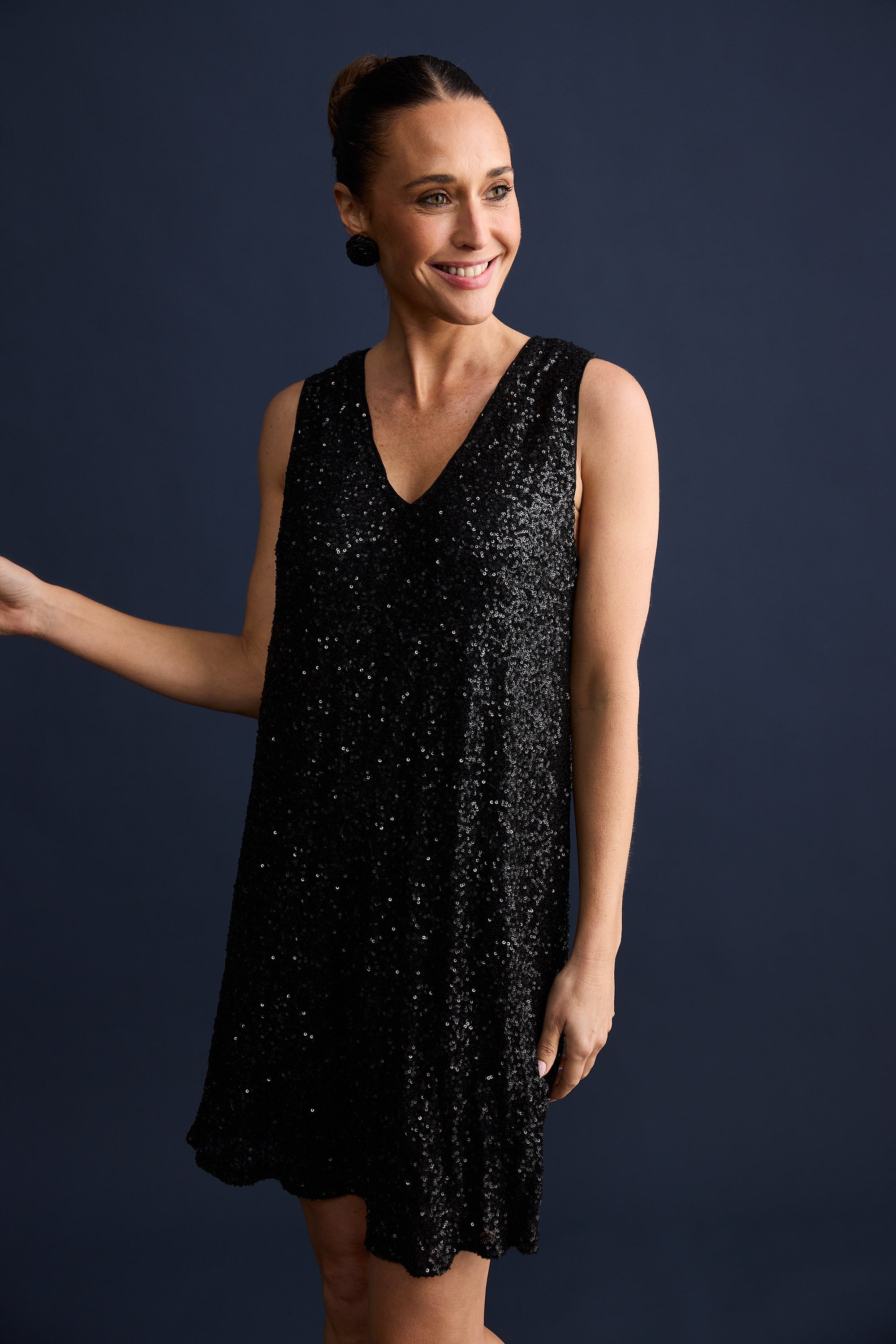 Woman wearing a black sequin dress against a dark background