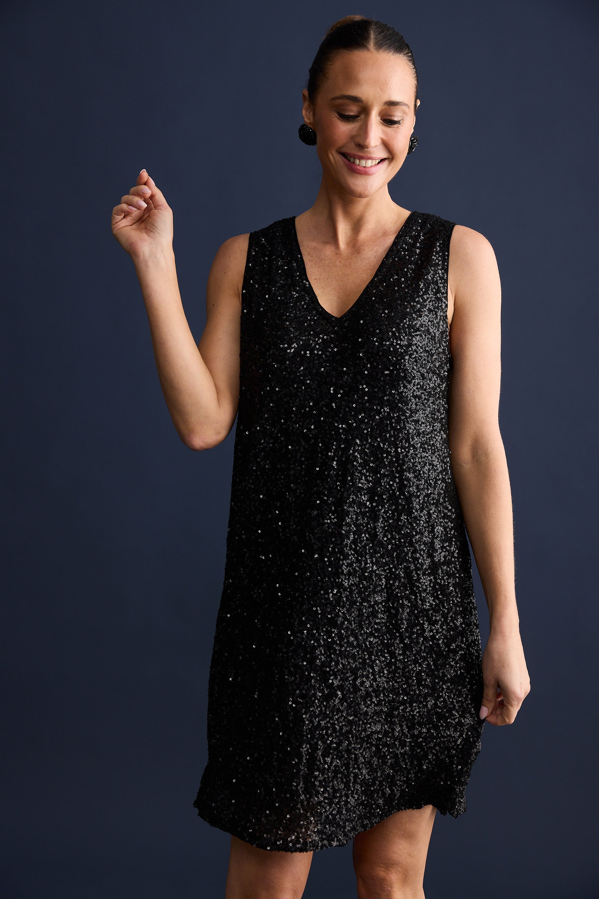 Woman wearing a black sequin dress against a dark background