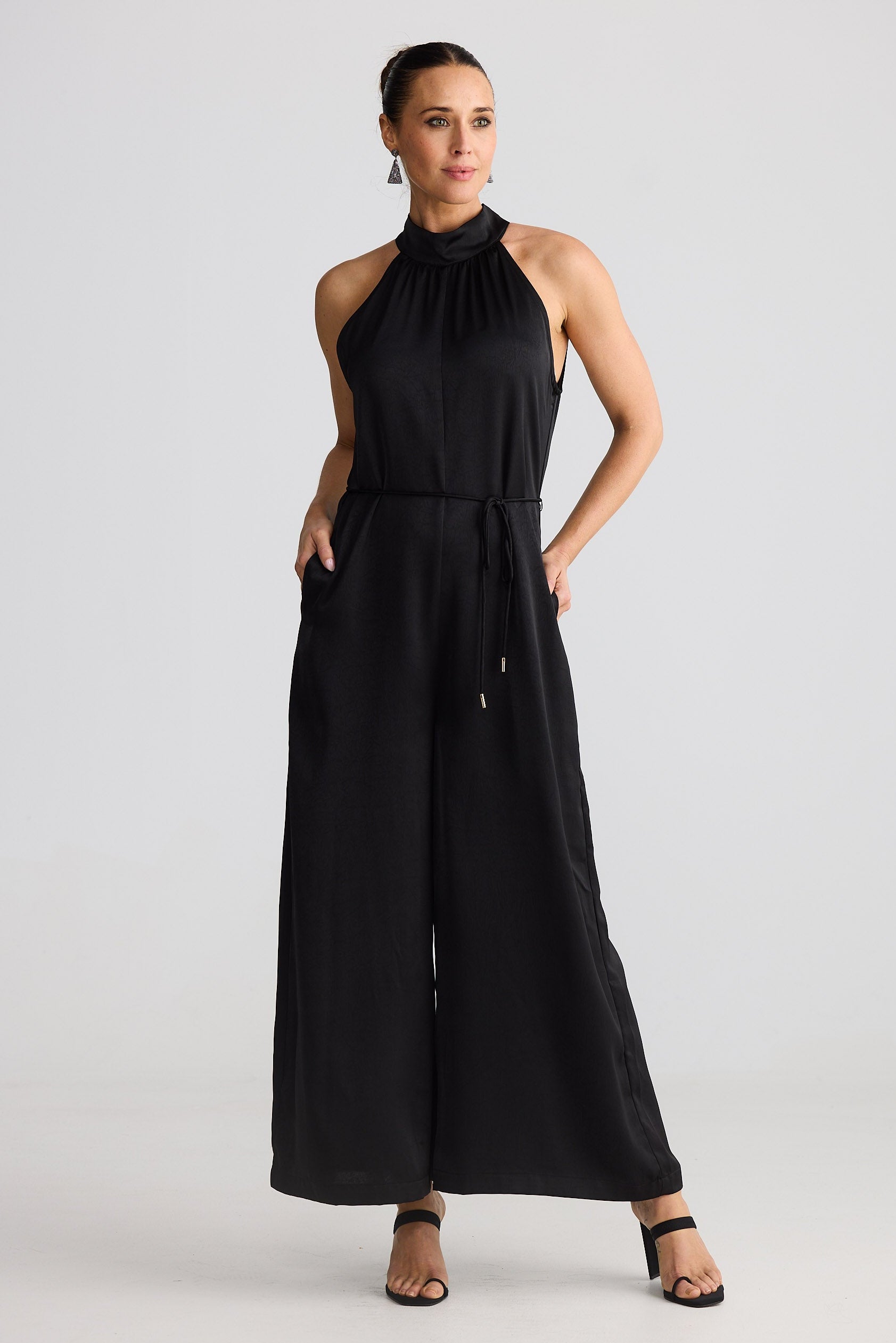 Woman wearing a black halter neck jumpsuit on a white background