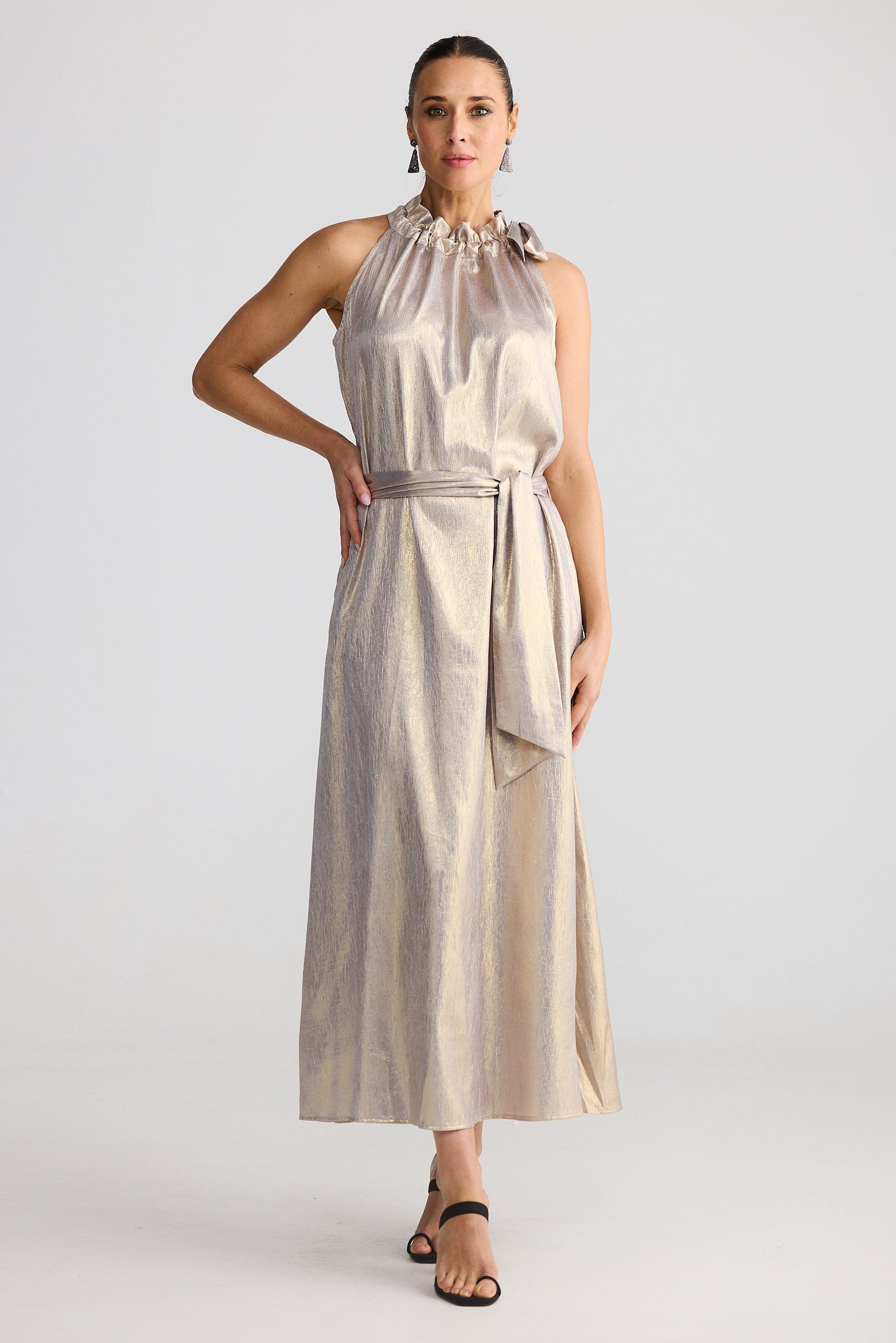 Woman wearing a beige sleeveless dress with a belt on a white background