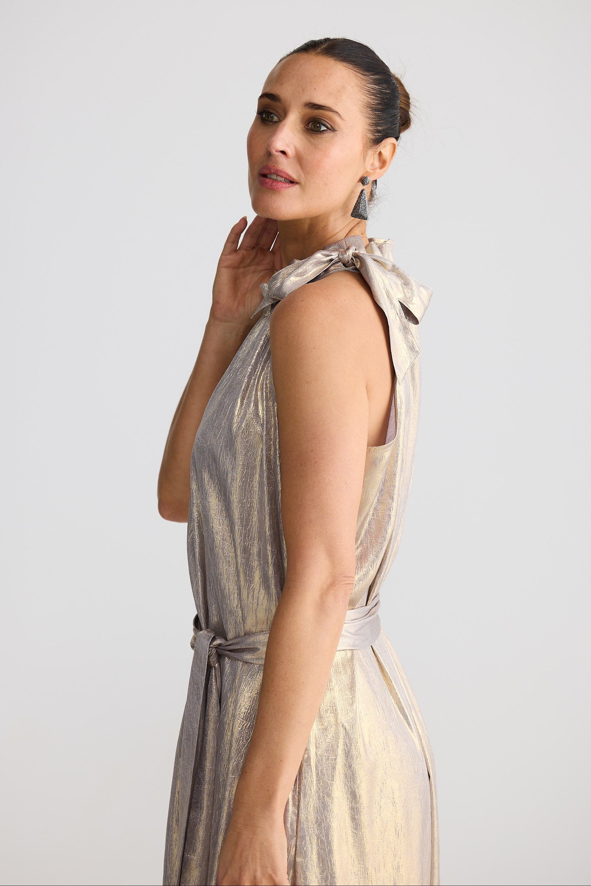 Woman wearing a sleeveless dress with a belt against a plain background