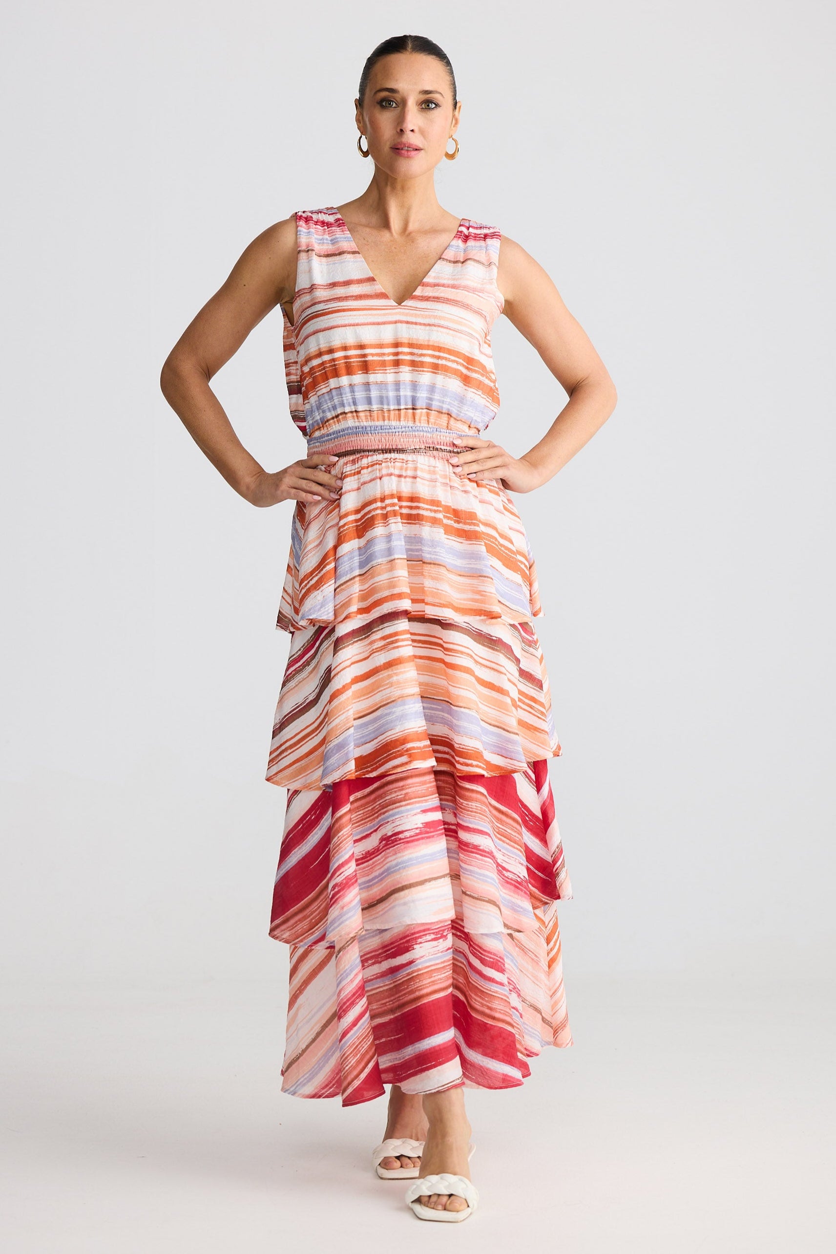 Woman wearing a sleeveless, long, multicolored dress against a plain background