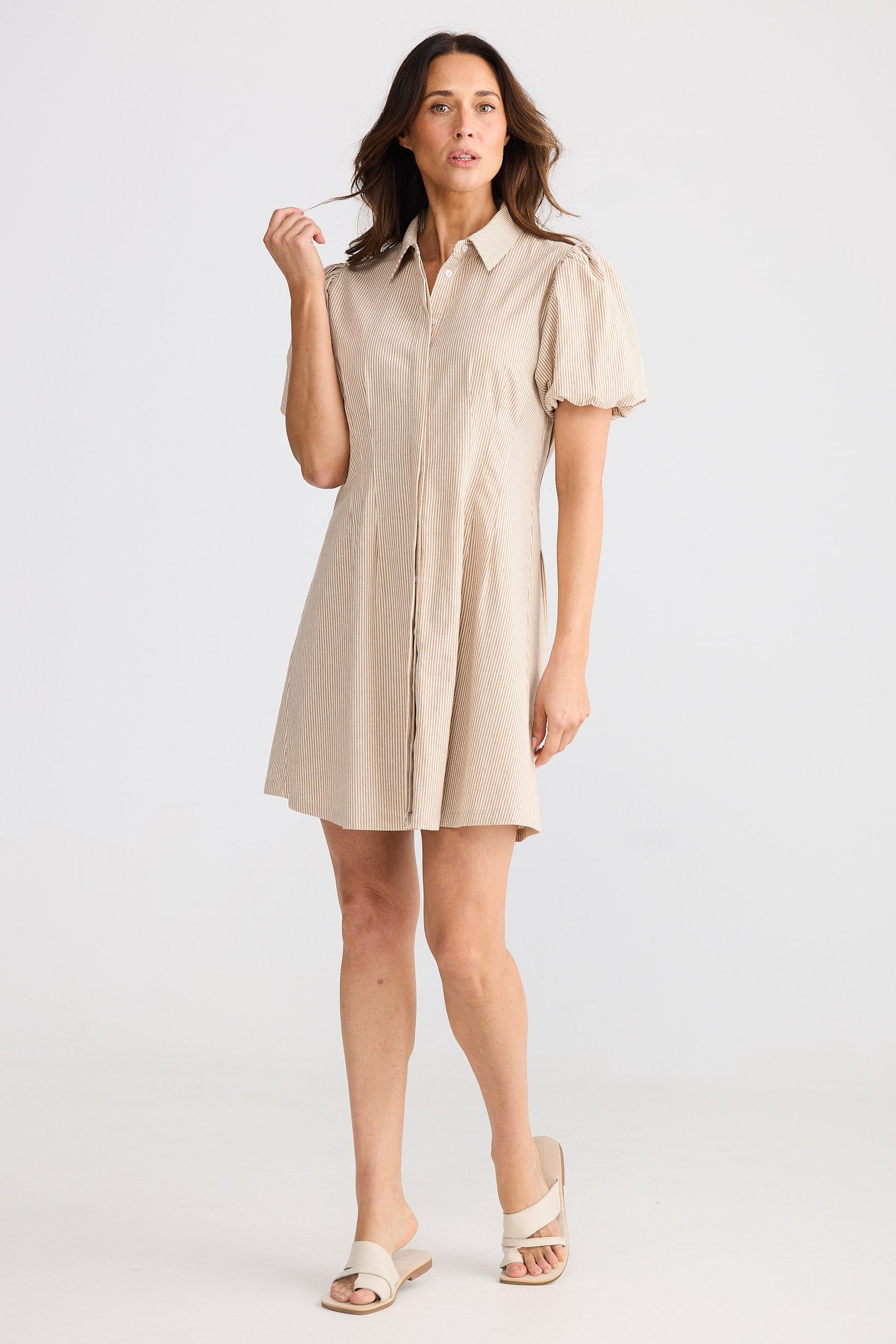 Woman wearing a beige shirt dress on a white background