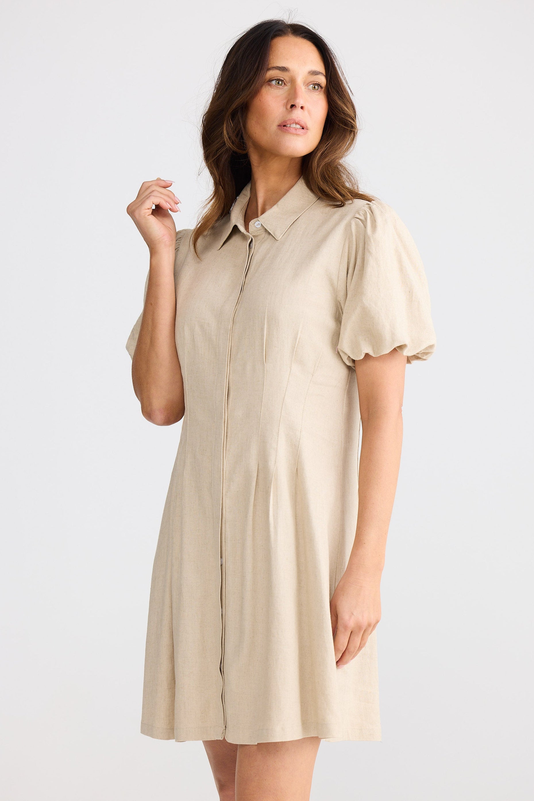 Woman wearing a beige shirt dress against a white background