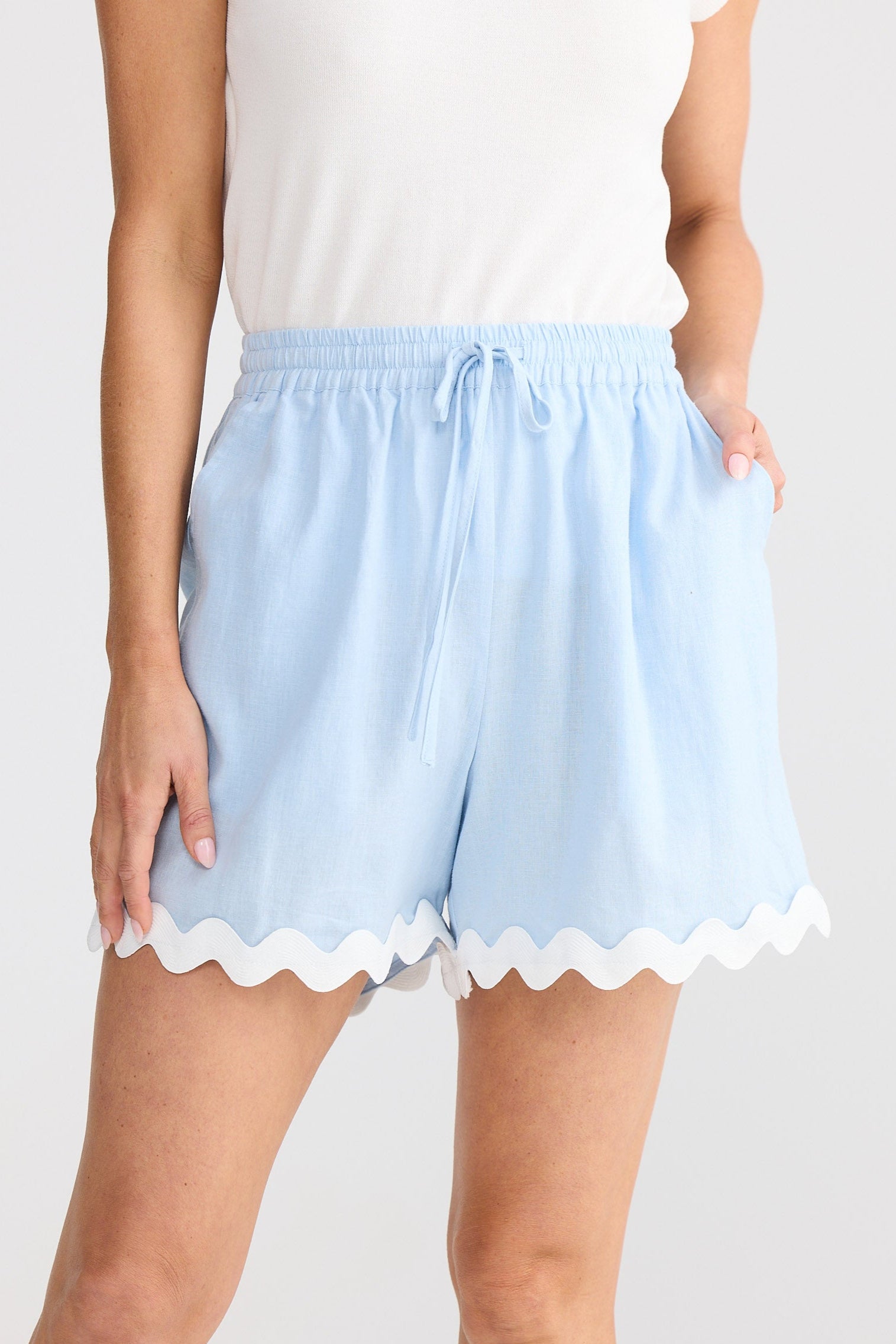 Light blue shorts with scalloped hem worn by a person on a white background