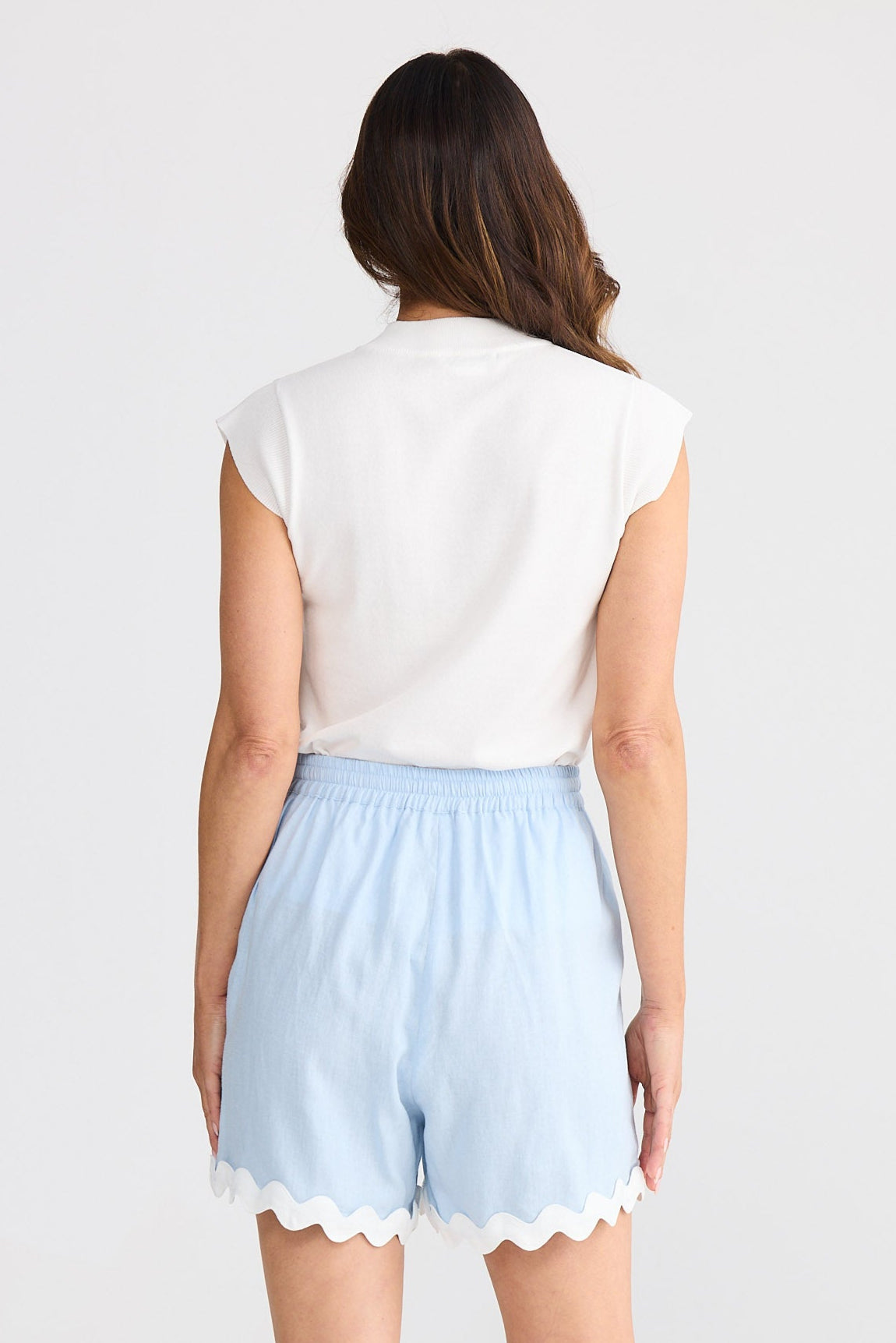Woman wearing light blue shorts with ric rac trim on a white background