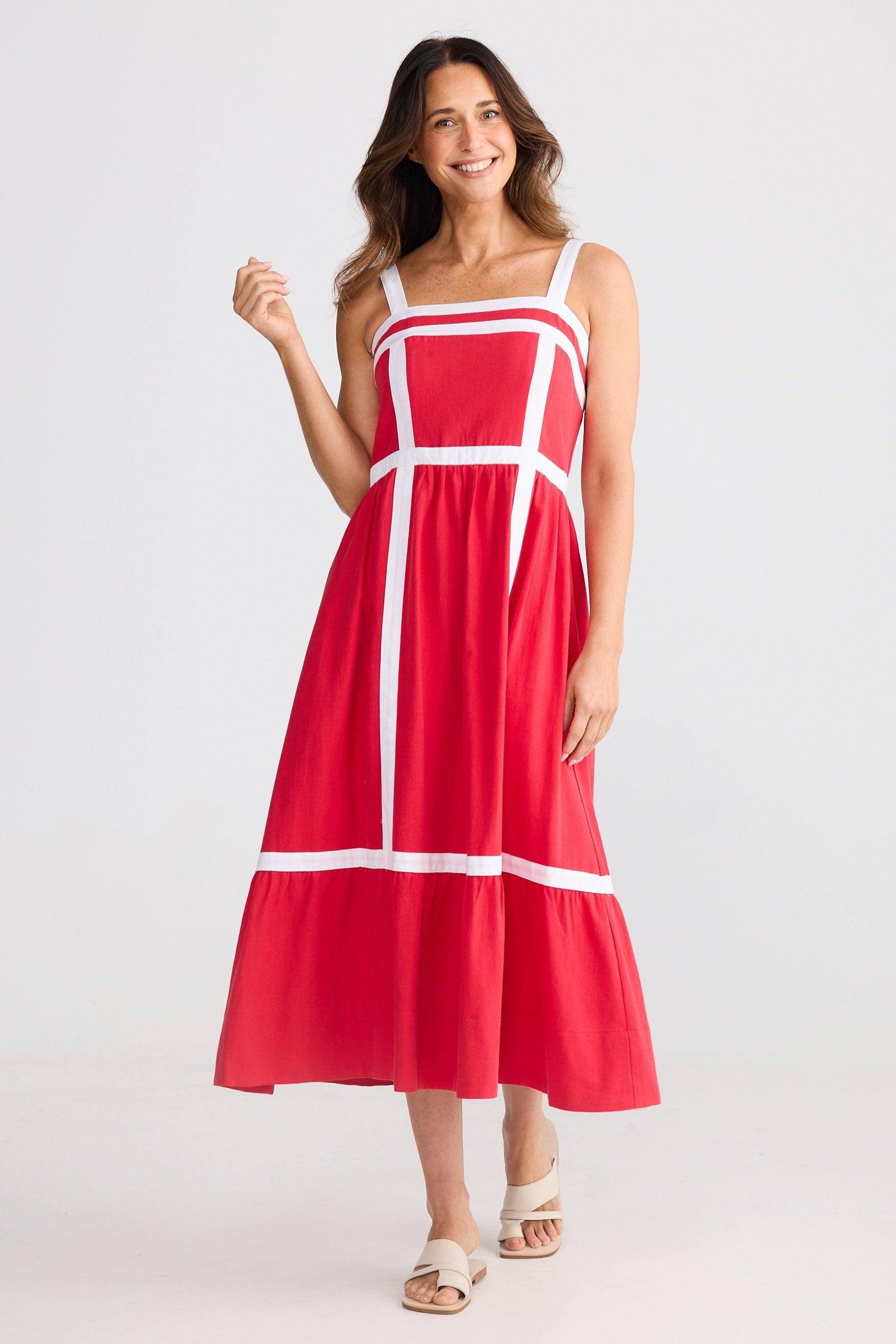 Woman wearing a red dress with white accents on a plain background