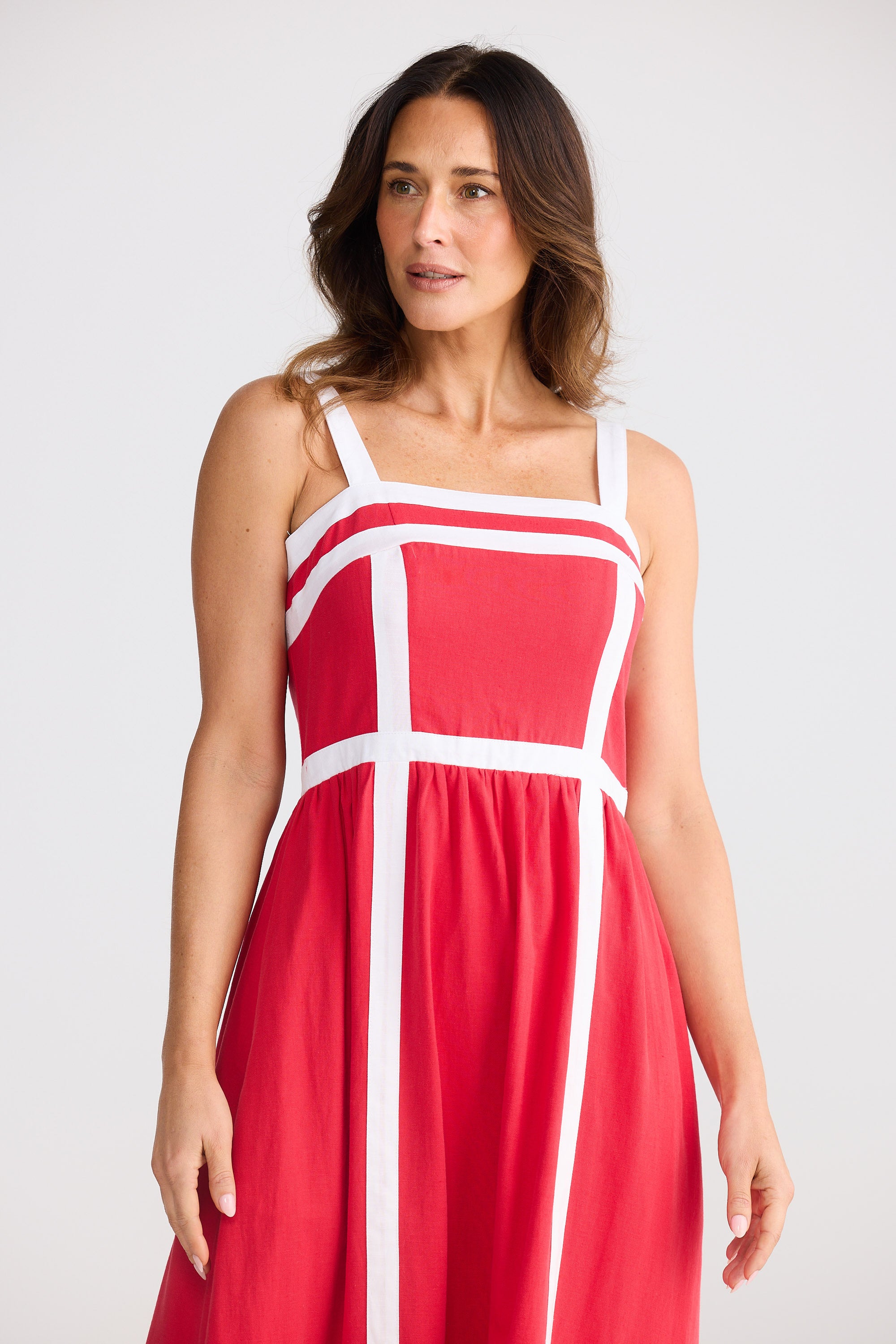 Woman wearing a red dress with white straps against a plain background