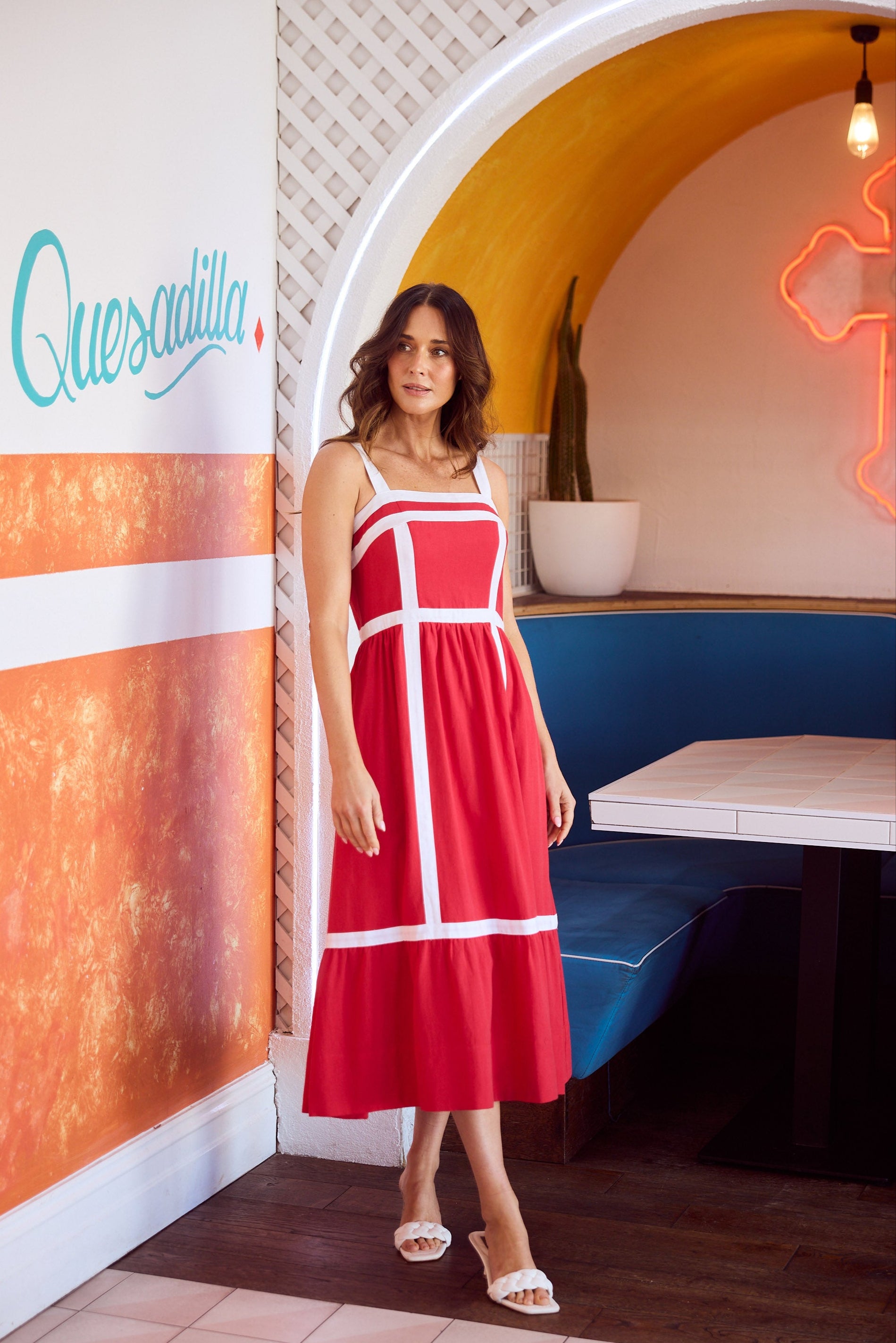 Woman in a red dress standing in a colorful indoor setting bright walls