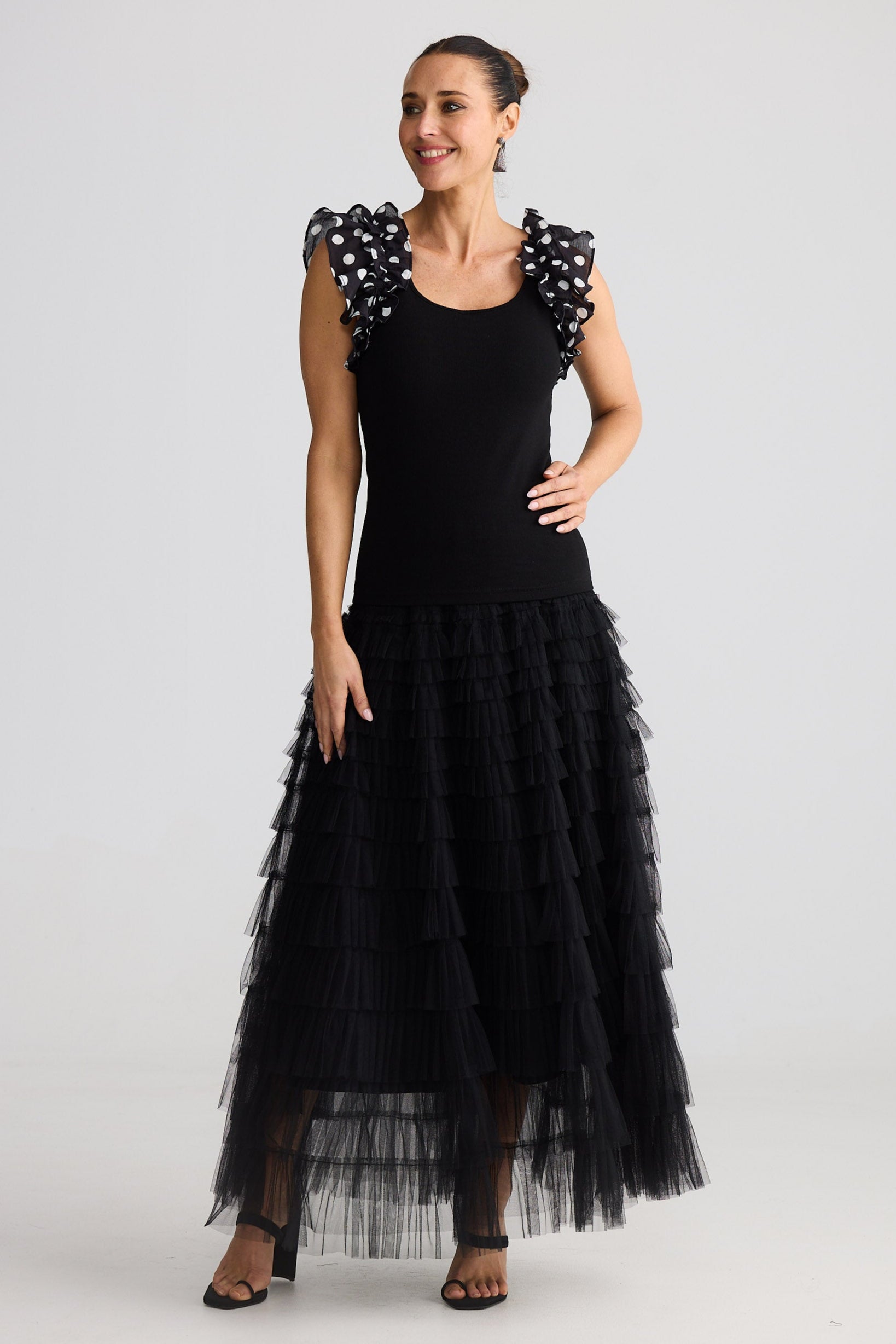 Woman wearing a black top with polka dot sleeves and black skirt on a white background