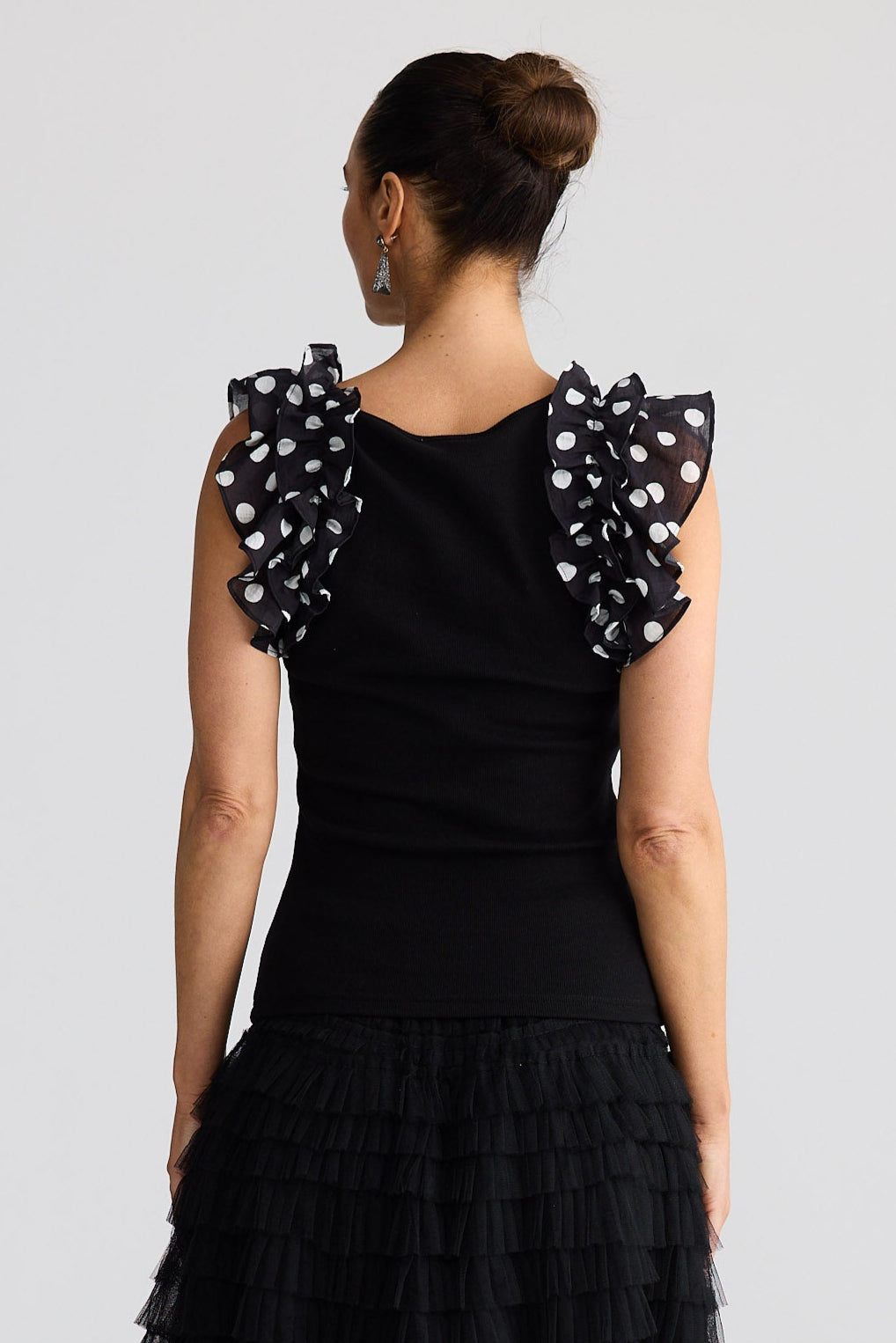 Woman wearing a black top with polka dot sleeves and black skirt on a white background