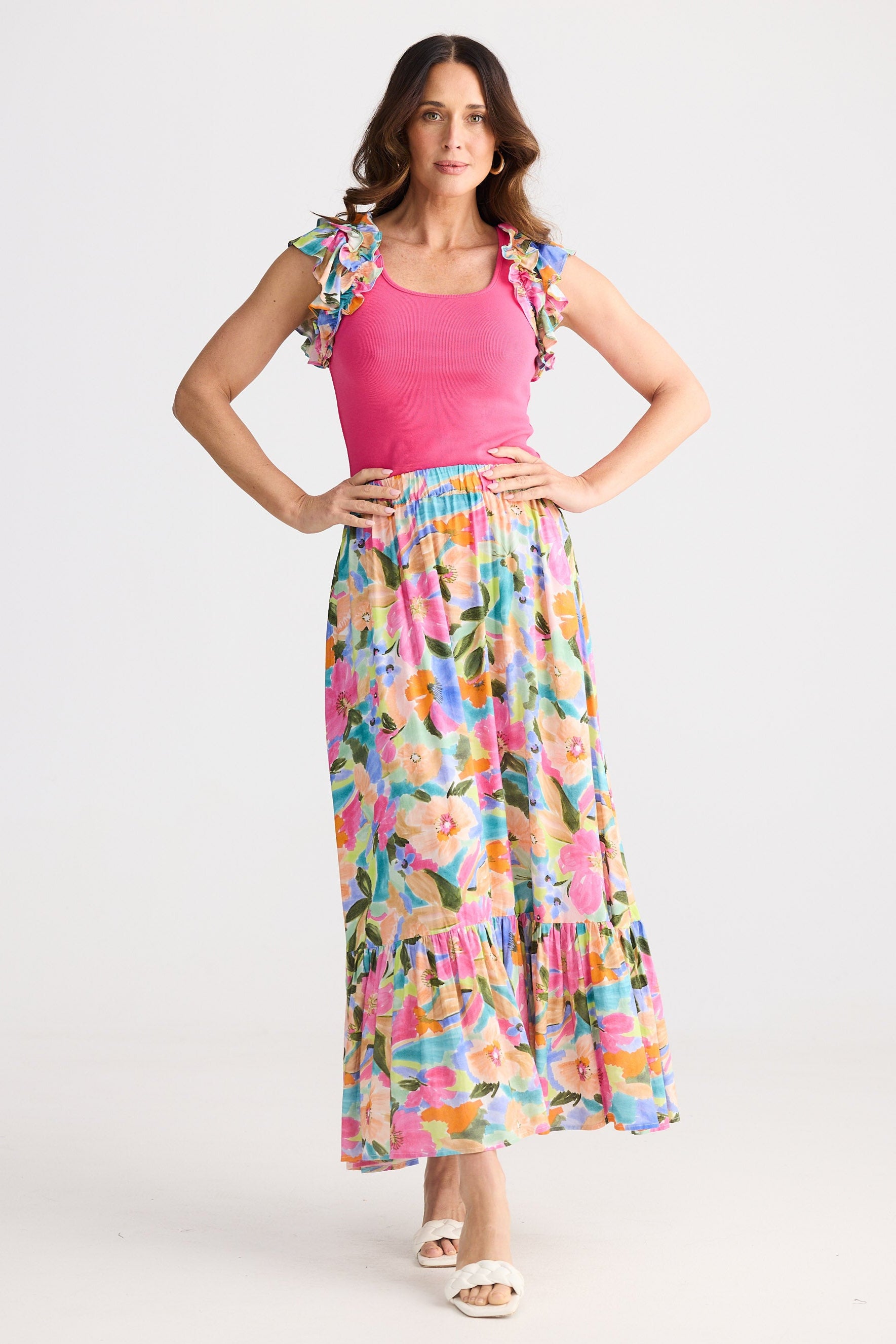 Woman wearing a pink top and colorful floral skirt on a white background